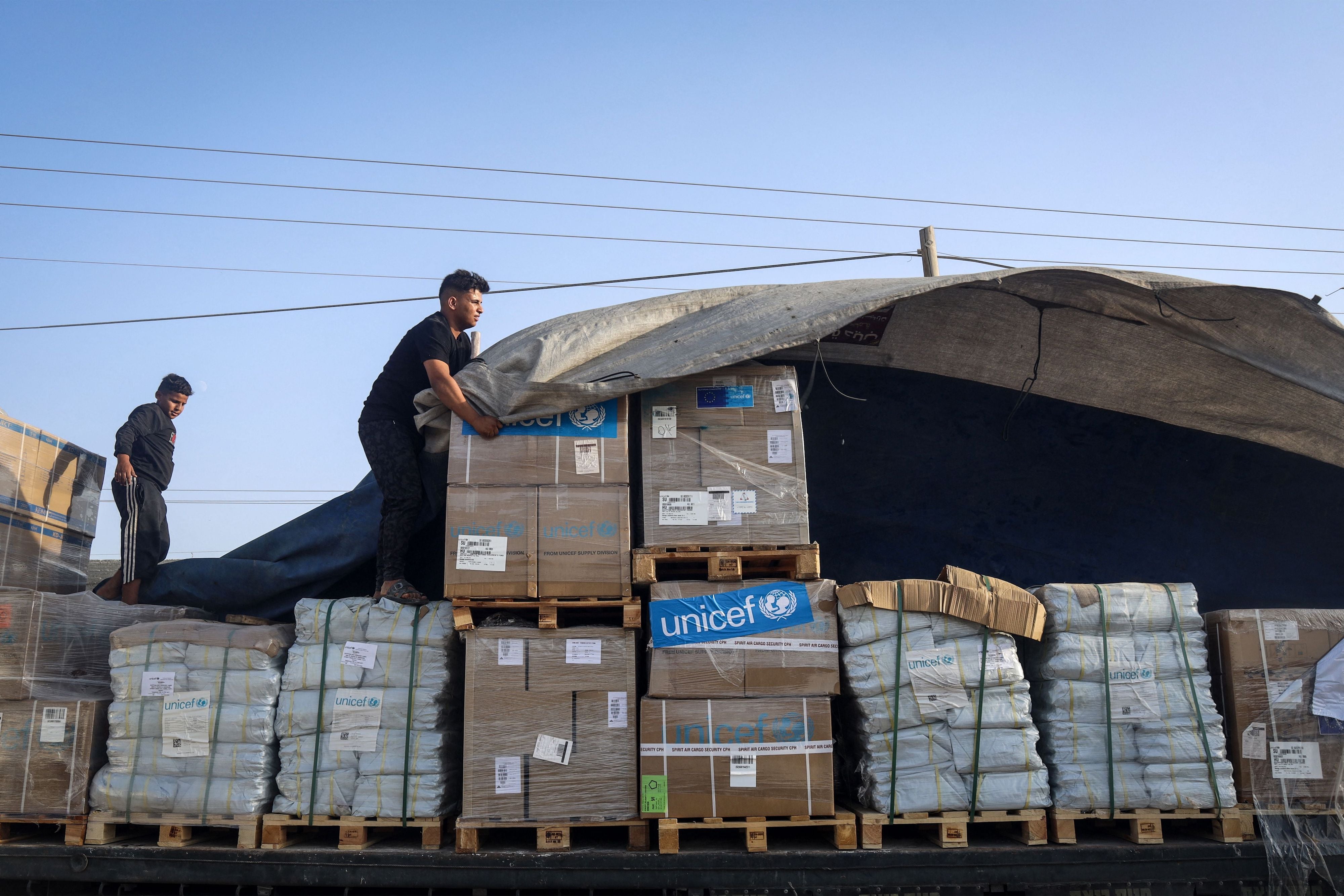 Un homme retirait la couverture au-dessus de colis contenant des produits d’aide humanitaire fournis par l’UNICEF, et livrés par des camions en provenance de l’Égypte, au poste-frontière de Rafah dans le sud de la bande de Gaza, le 21 octobre 2023.