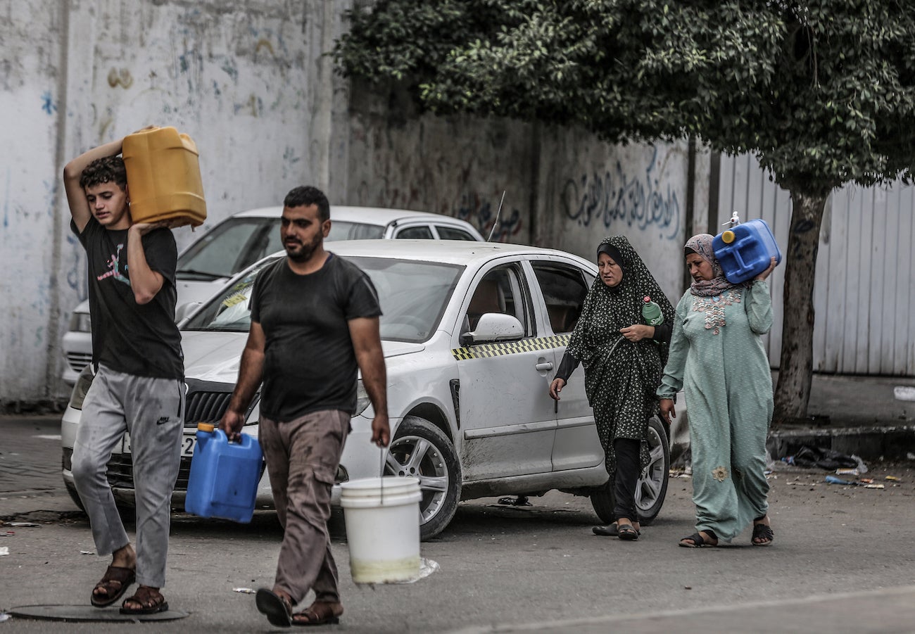Palestinians carry their bottles of water after Israeli authorities have ceased supplying electricity, water and food in the Gaza Strip, October 17, 2023.