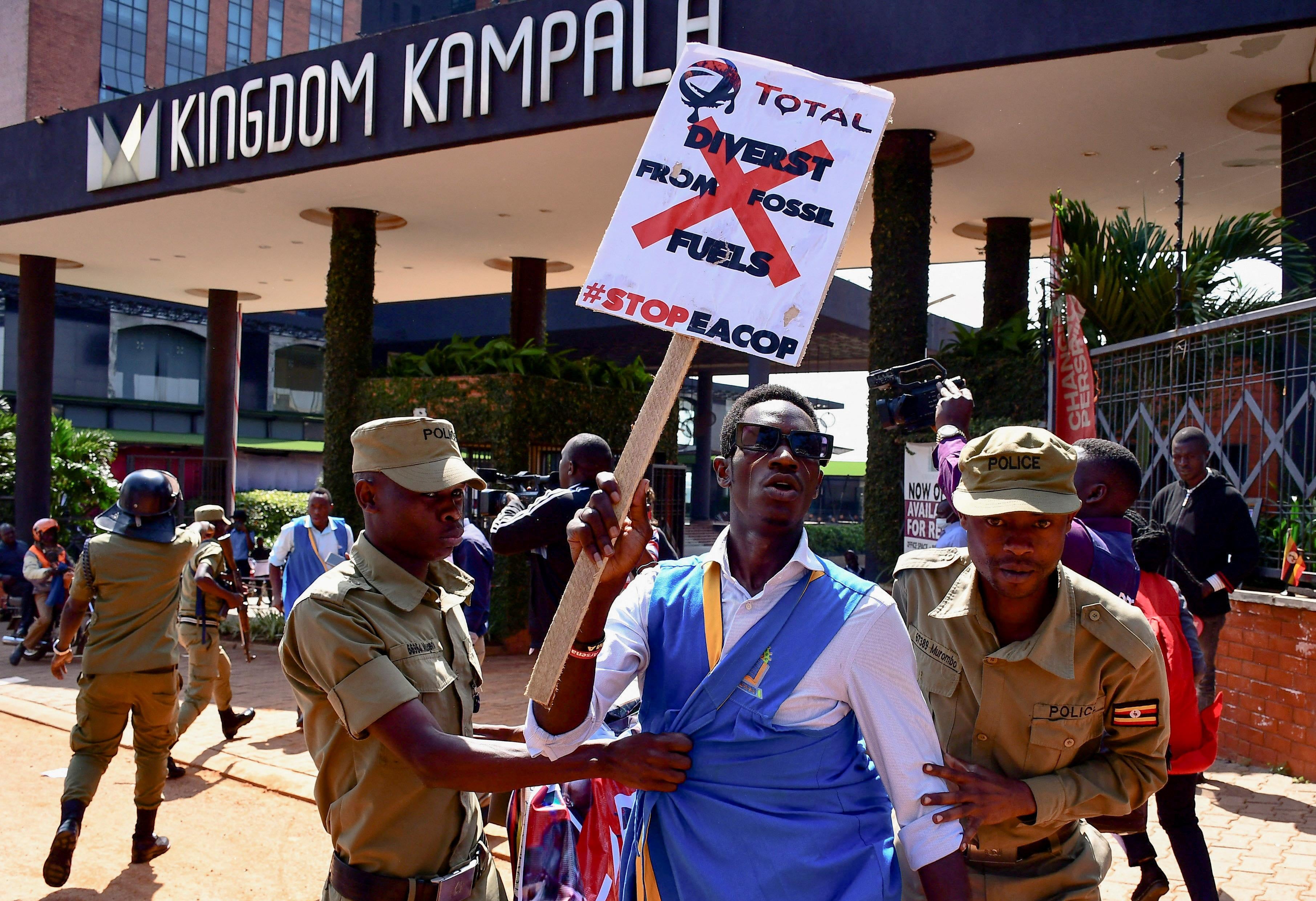 security officials detain a protester holding a placard