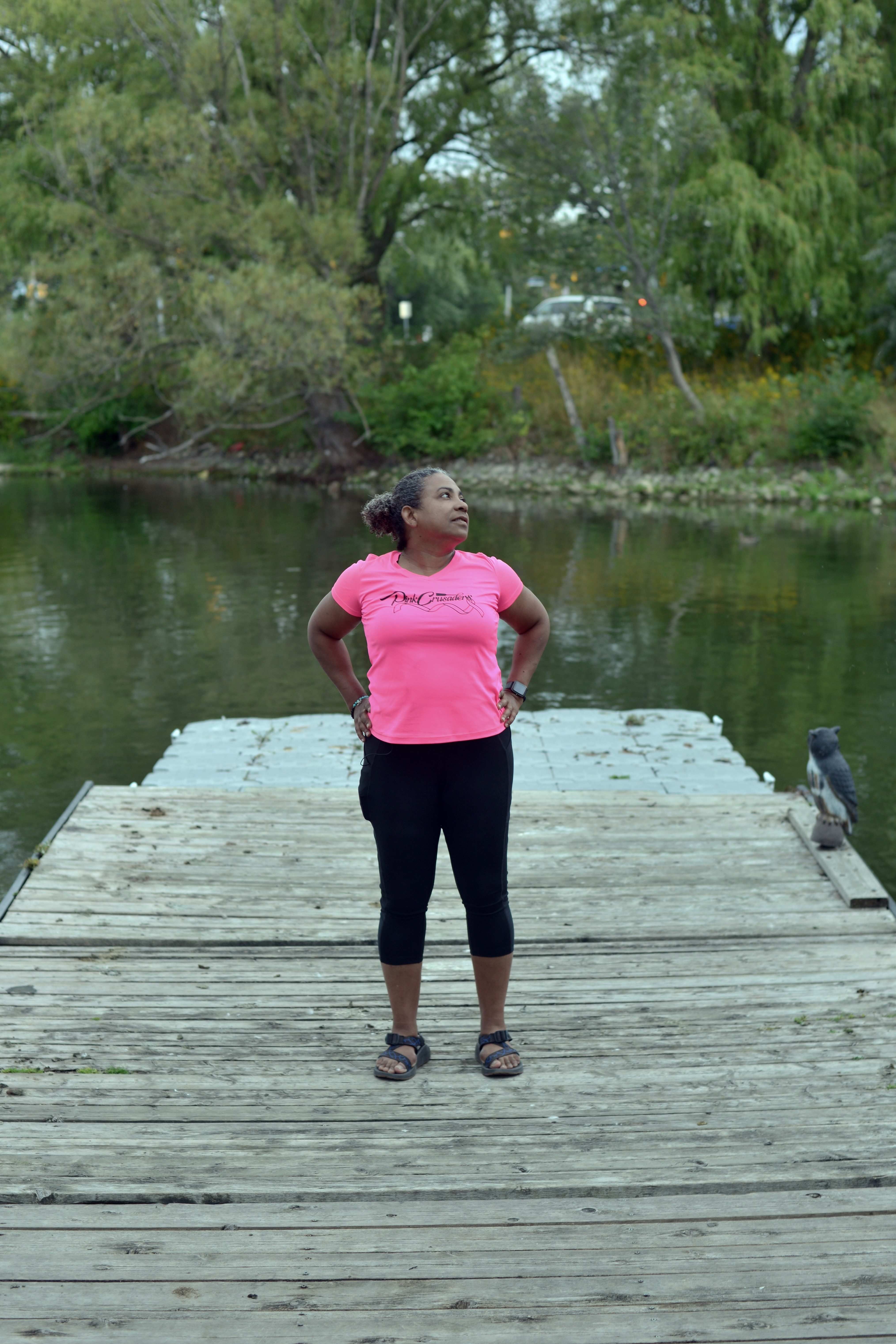 A woman stands on a dock in a lake