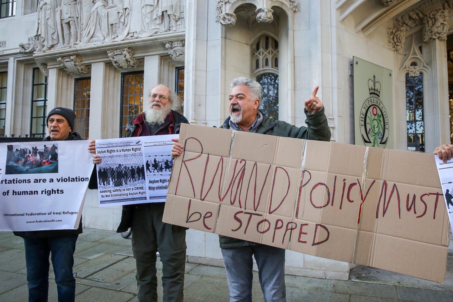 Des manifestants opposés à un accord entre le Royaume-Uni et le Rwanda prévoyant l’expulsion au Rwanda de demandeurs d’asile brandissaient des pancartes devant la Cour suprême a Londres, le 15 novembre 2023. 