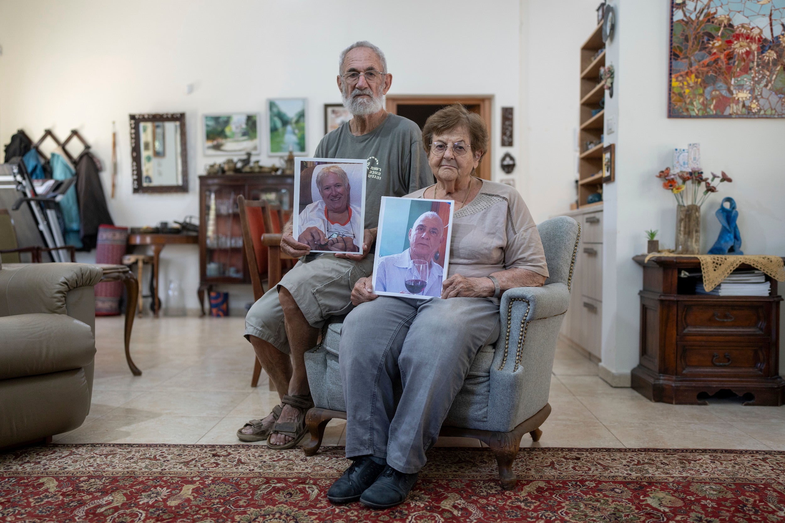 חנן ועדנה כהן אוחזים בתמונותיהם של אחותו בת ה-77 של חנן, מרגלית מוזס, ובעלה בן ה-79, גדי מוזס, בביתם שבלכיש, 30 באוקטובר 2023. בני הזוג מוזס נחטפו מביתם שבקיבוץ ניר עוז במתקפה בראשות חמאס ב-7 באוקטובר 2023.