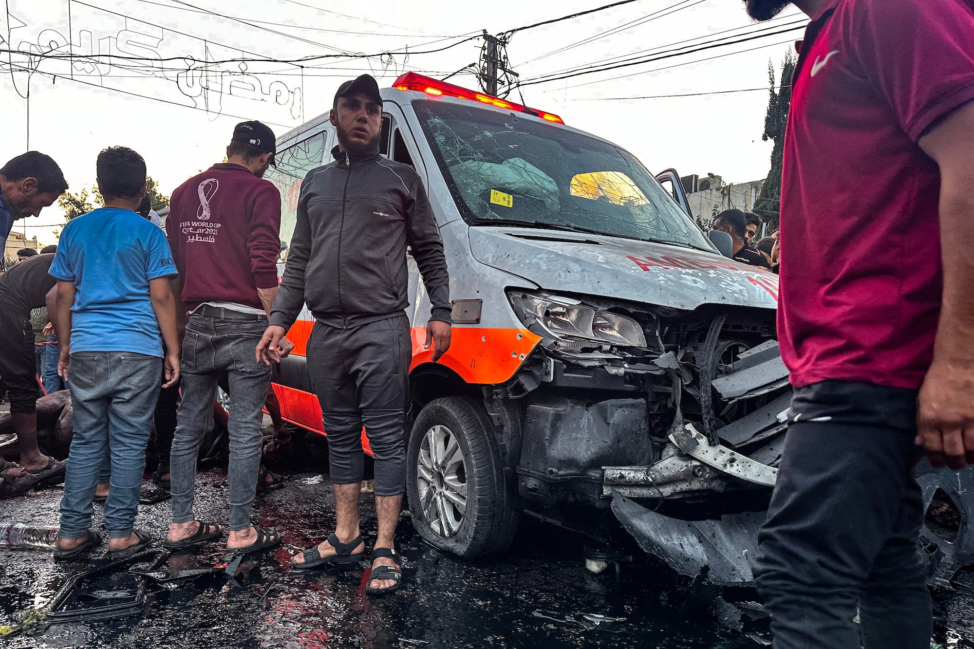 People gather around an ambulance damaged in a strike in front of Al-Shifa hospital in Gaza City on November 3, 2023. 