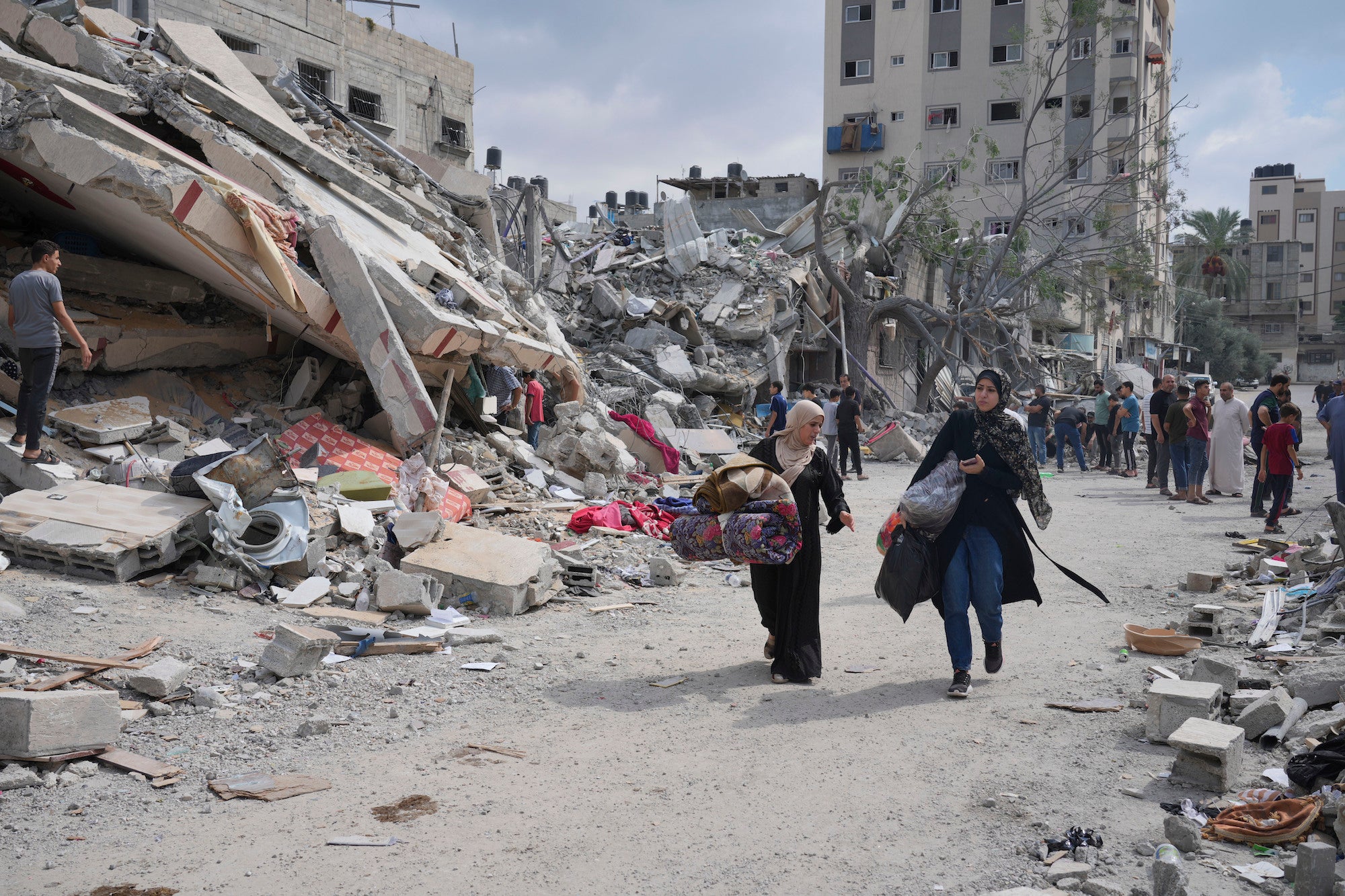 Palestinian women walk by buildings destroyed in Israeli airstrikes in Nuseirat camp in the central Gaza Strip, October 16, 2023.