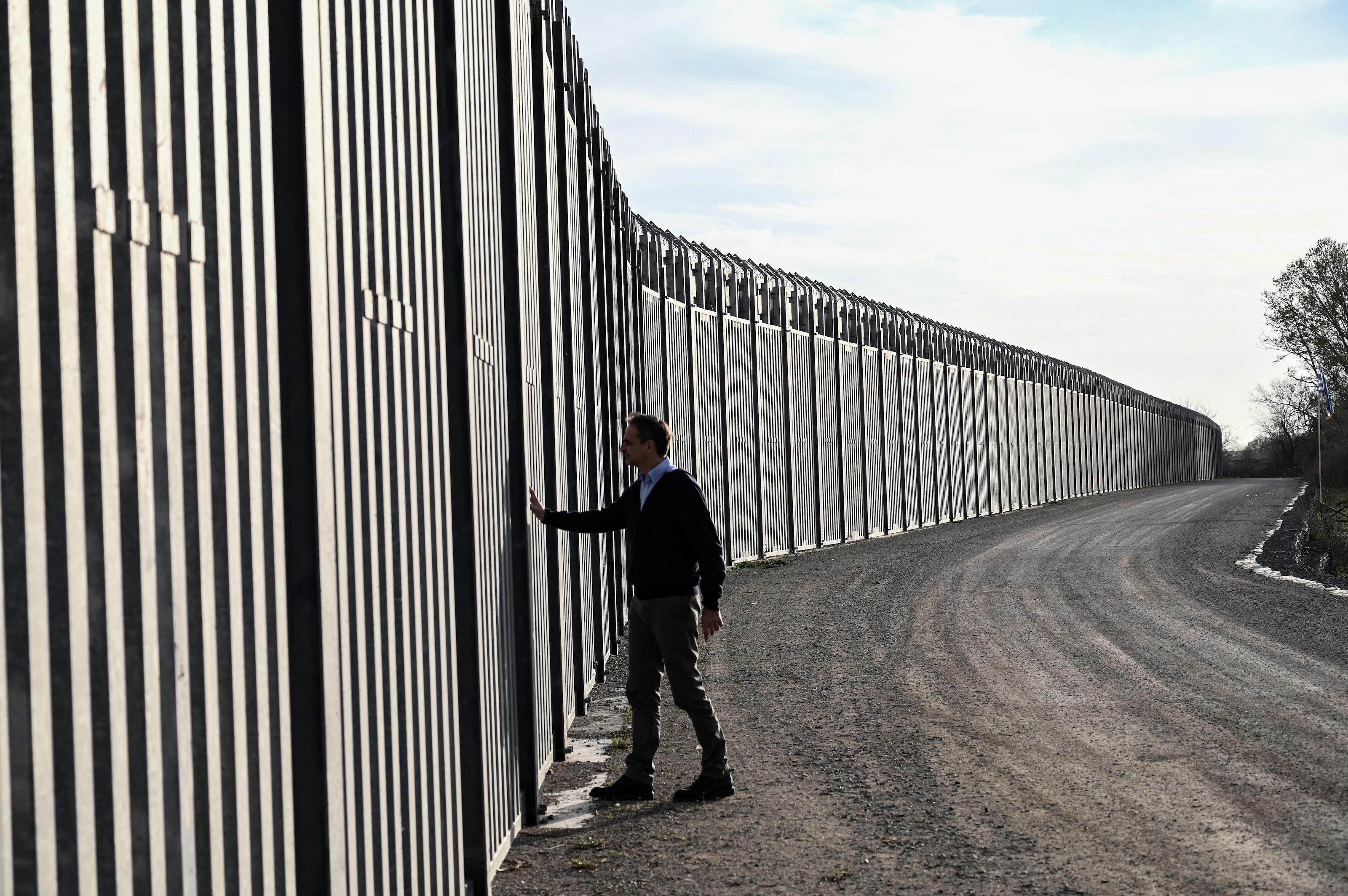 Greek Prime Minister Kyriakos Mitsotakis walks next to a  steel fence during a ceremony marking the signing of the extension to the country's steel fence on the border with Turkey, in Feres on March 31, 2023. 