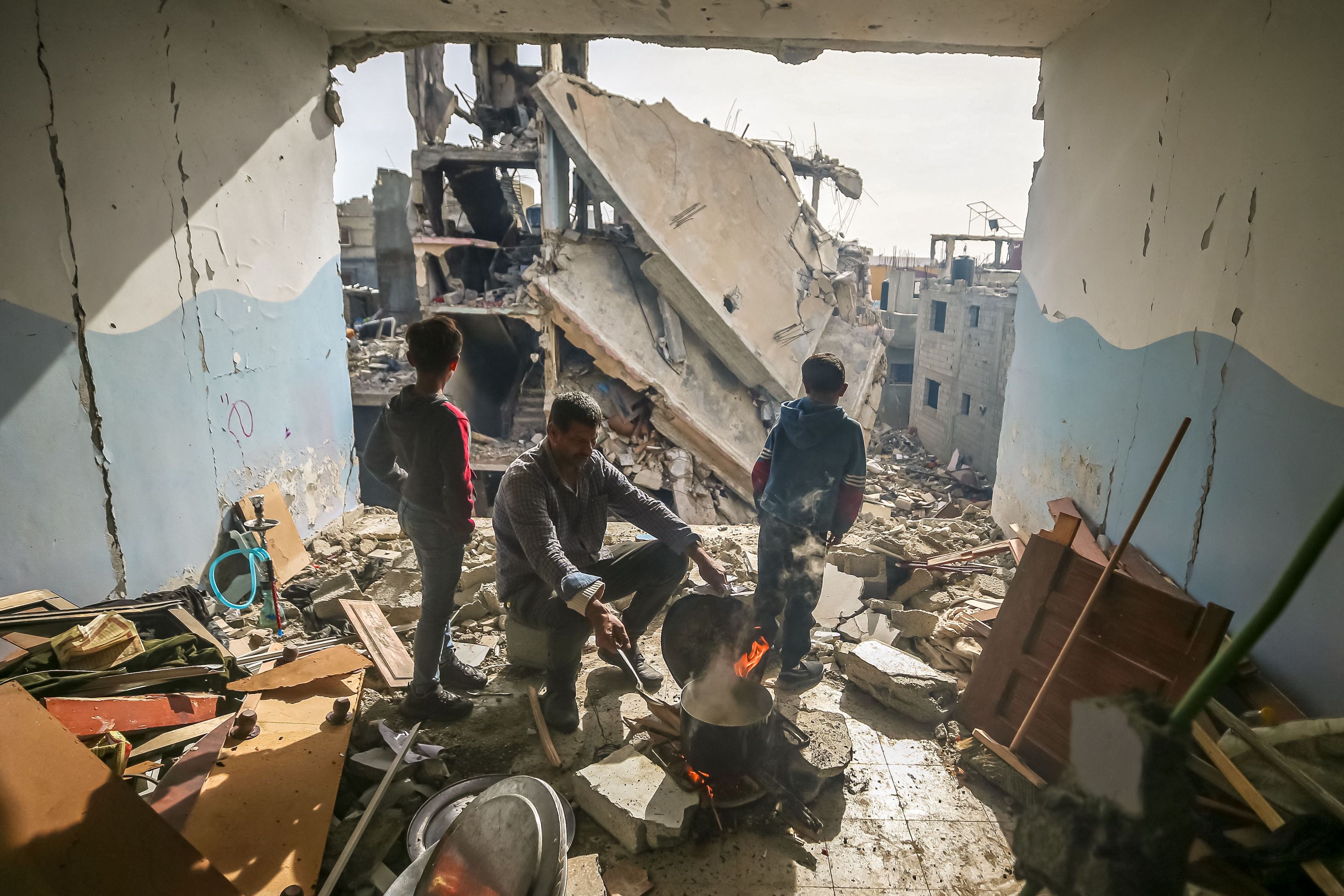 A man cooks inside his damaged apartment in the Khezaa district in Khan Yunis, Gaza, November 25, 2023. 