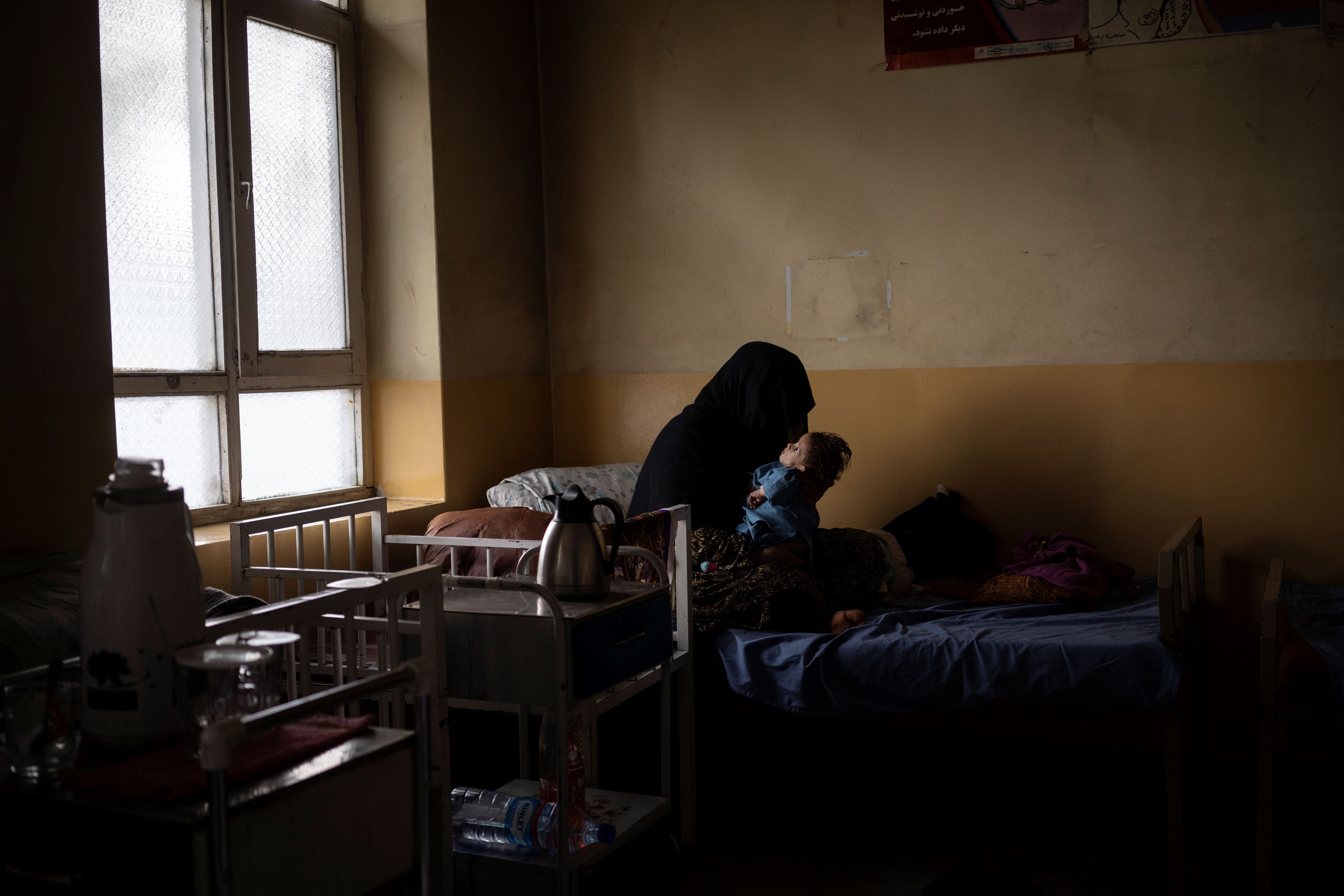 An unidentifiable woman holds her baby son on a hospital bed