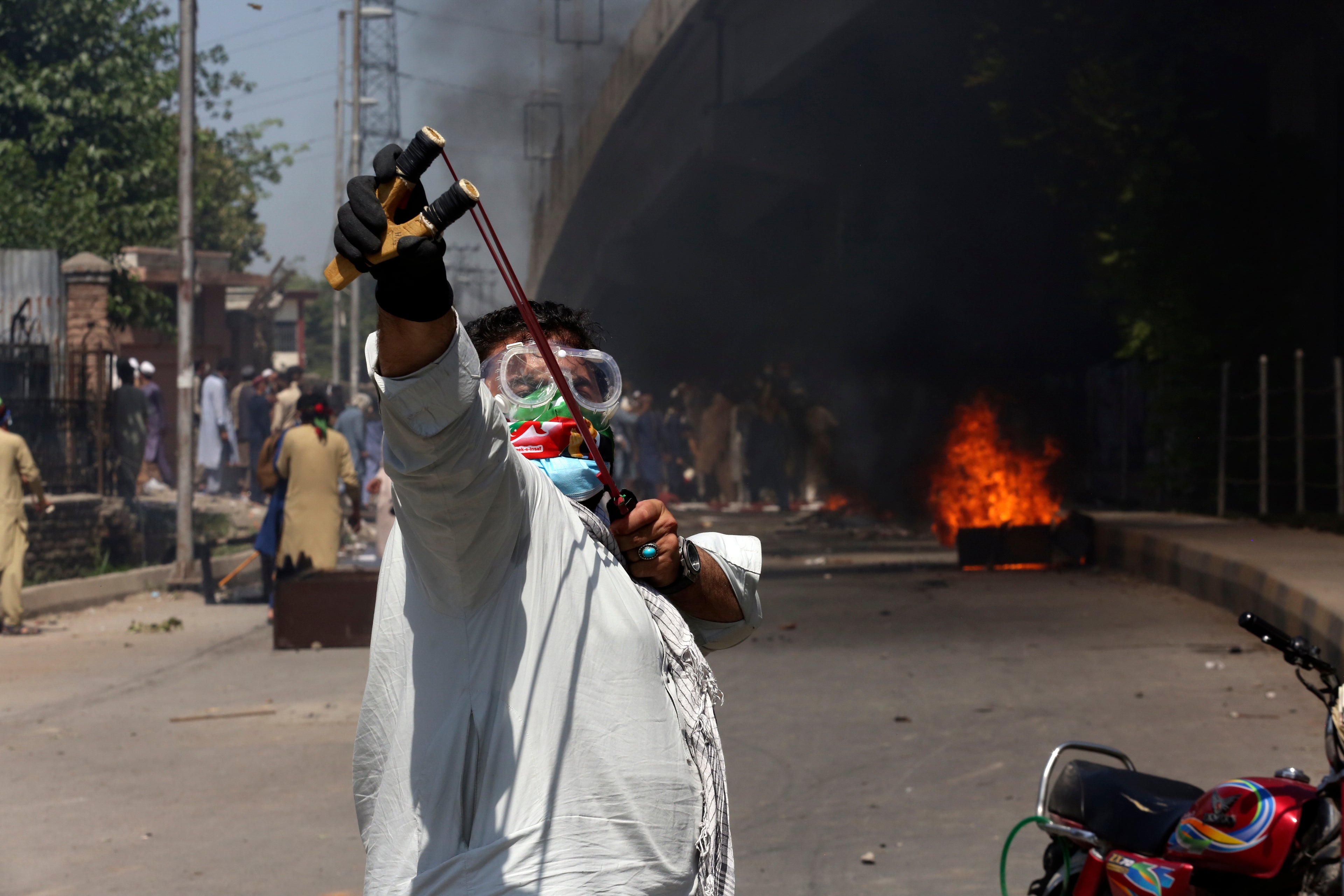A protester aims a slingshot towards police (unseen)