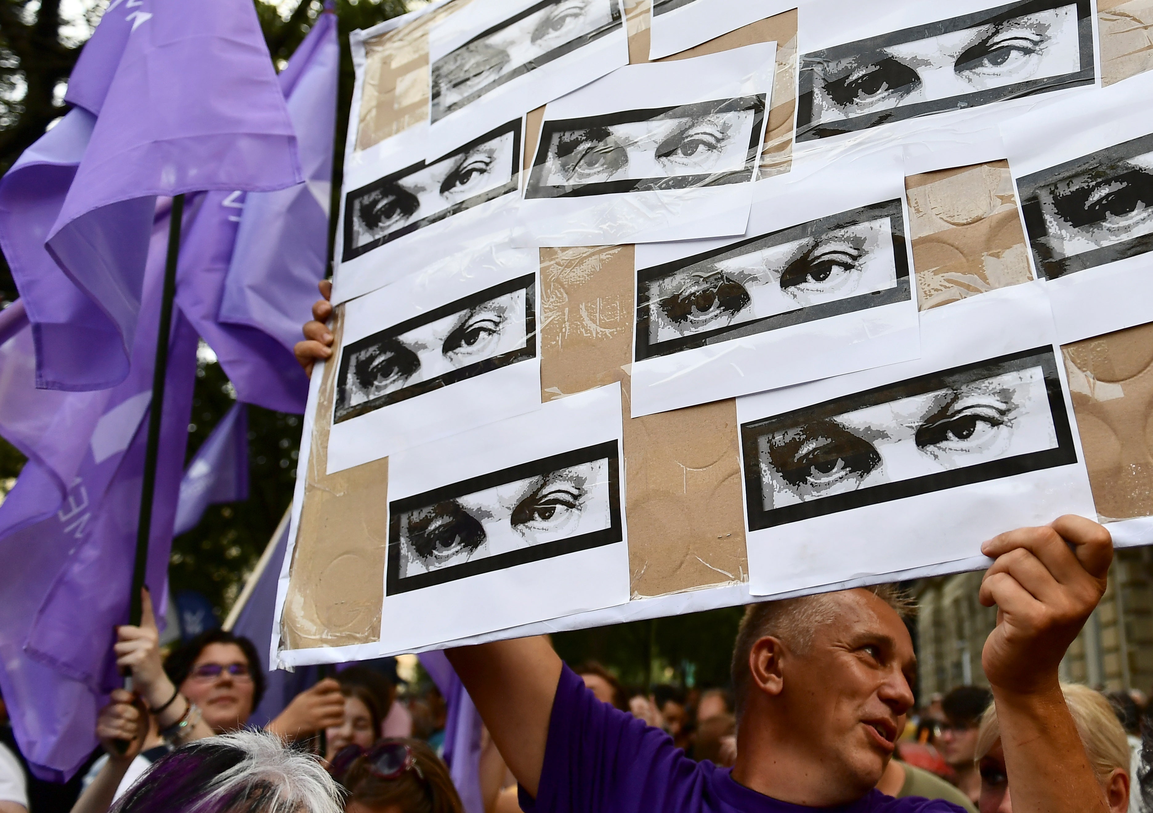 A man holds a banner showing the eyes of Hungarian Prime Minister Viktor Orban during a protest