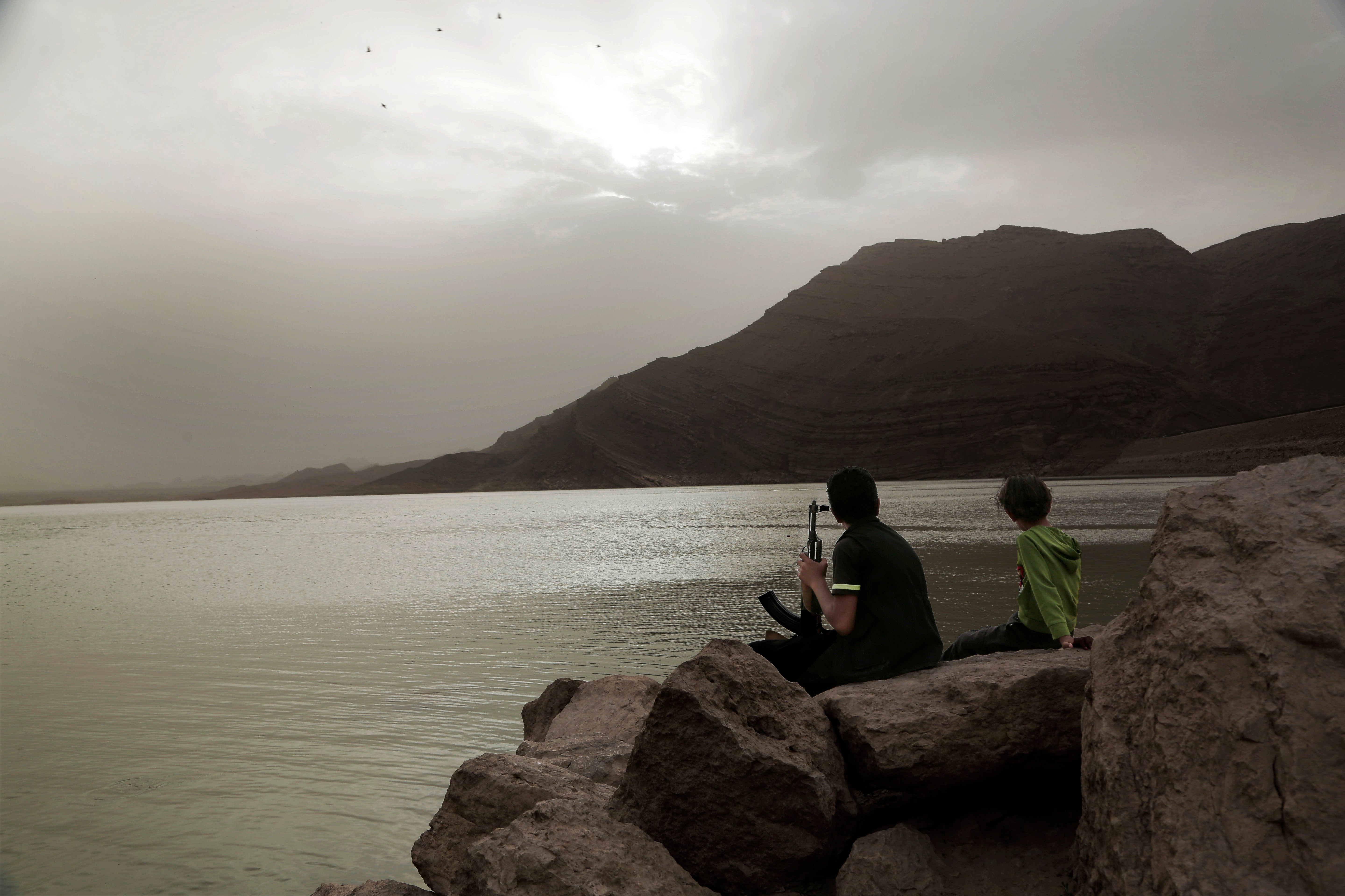 A boy, believed to be recruited by the Houthis, holds an AK-47 while overlooking the high dam in Marib, Yemen, July 30, 2018.