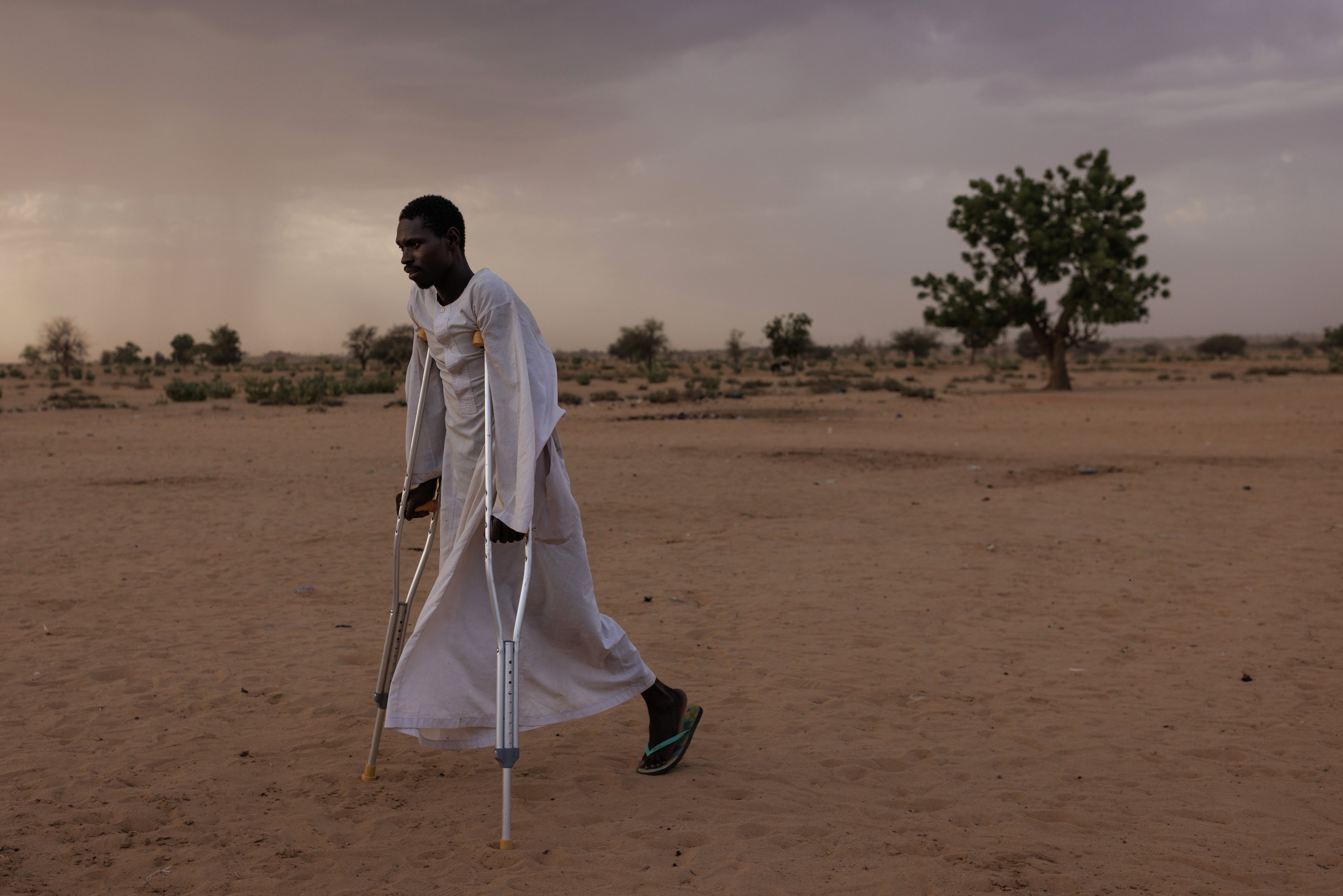 A man walks using crutches in a refugee camp