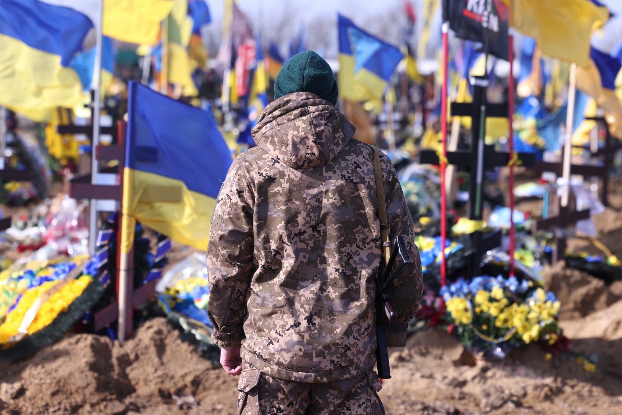 A Ukrainian soldier stands in front of the graves of Ukrainian soldiers killed in the war at a cemetery in Kharkiv.