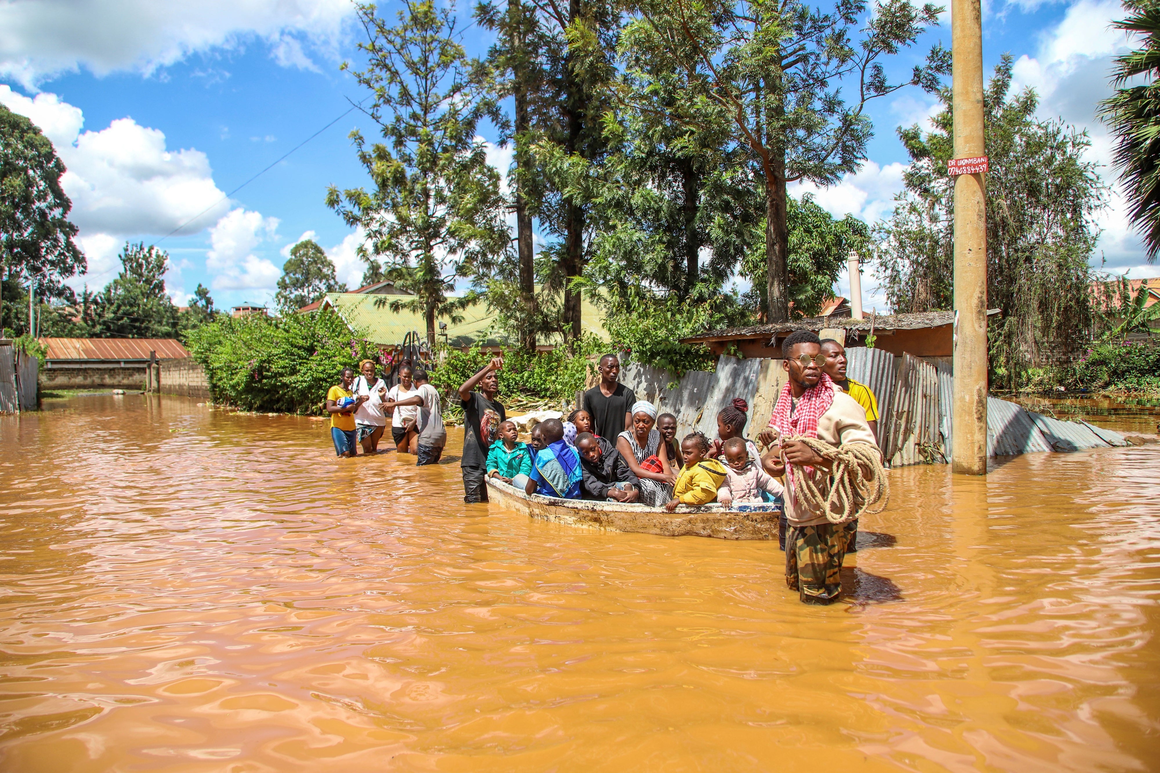 Une famille kenyane et d’autres personnes, dont de nombreux enfants dans un petit bateau, avançaient dans les eaux de crue dans le quartier de Githurai à Nairobi, au Kenya, le 24 avril 2024, suite aux pluies diluviennes qui ont frappé ce pays. 