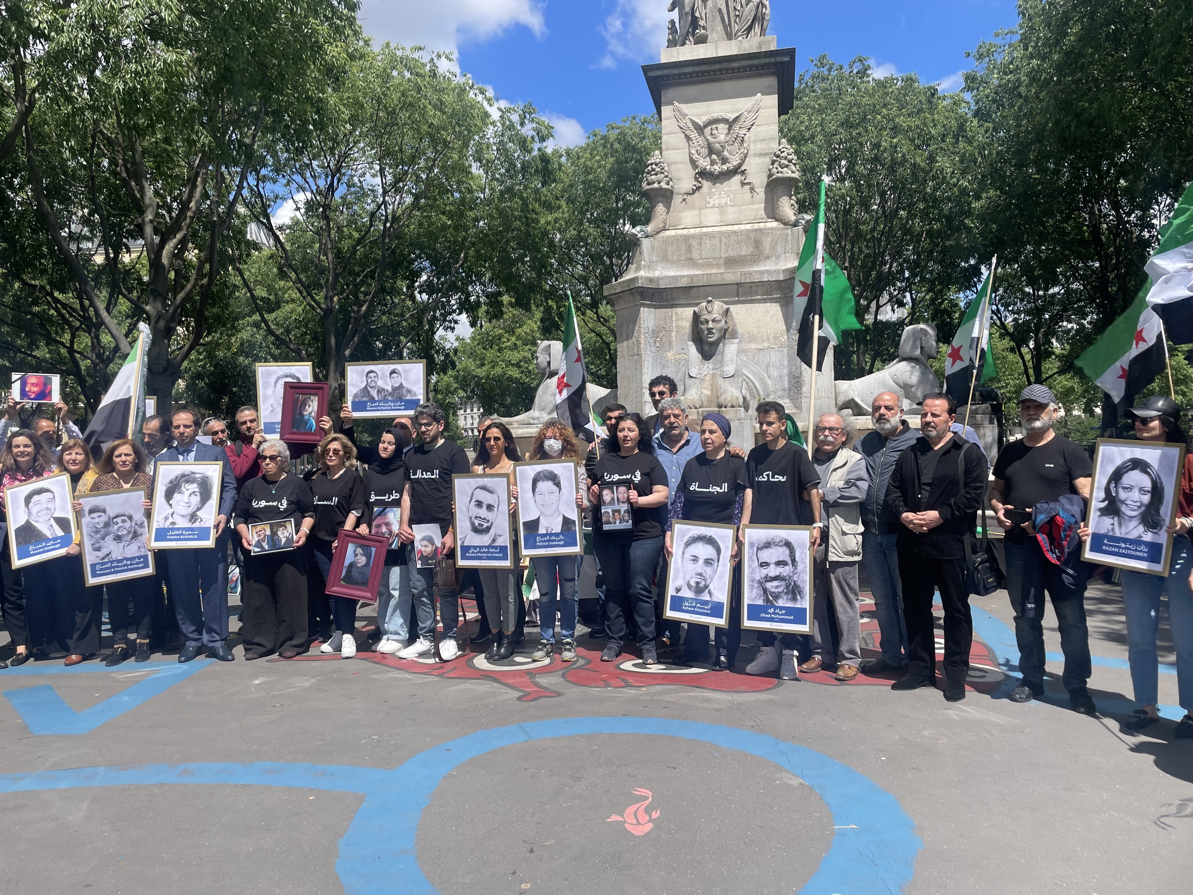Des associations de victimes et de familles se sont rassemblées à côté Tribunal de Paris le 21 mai 2024, tenant des photos de proches détenus ou disparus en Syrie.
