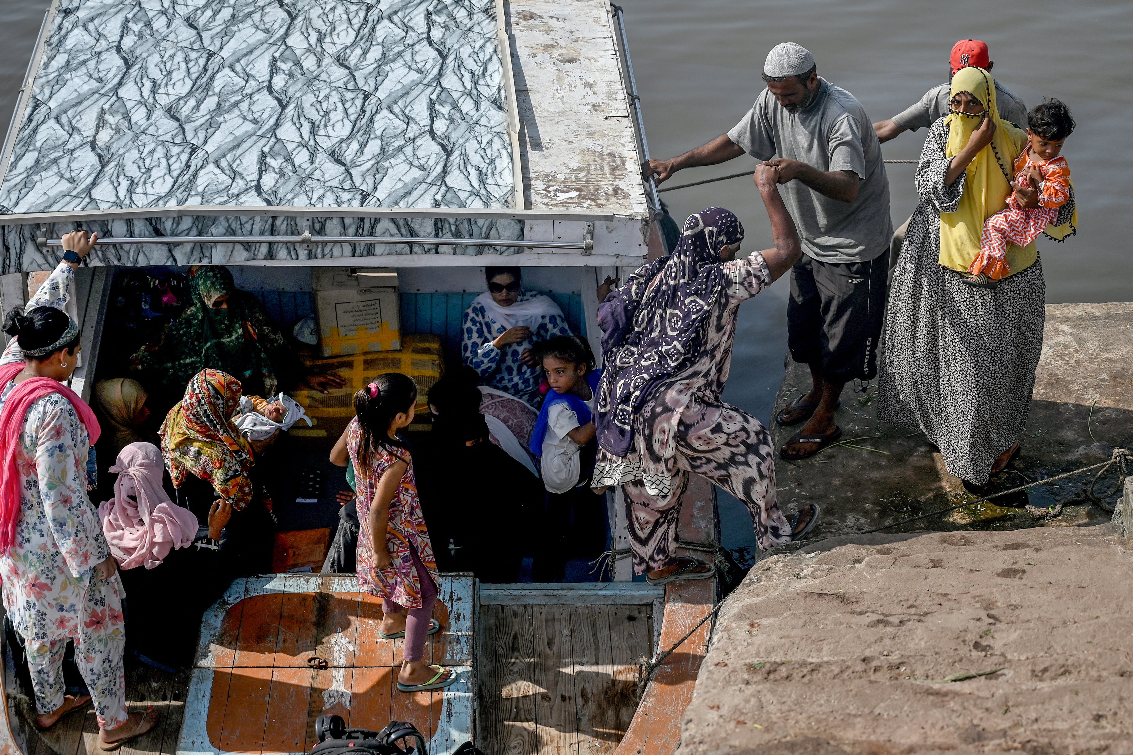 A group of women travel during a heatwave for medical consultation to the only midwife who arrives from the mainland to Baba Island along the Karachi Harbor, Pakistan, June 11, 2024.