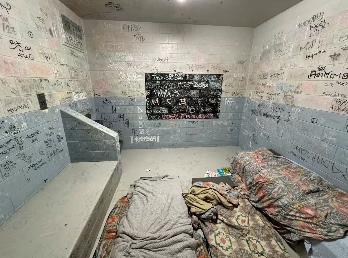 A detention cell with writing on its walls.