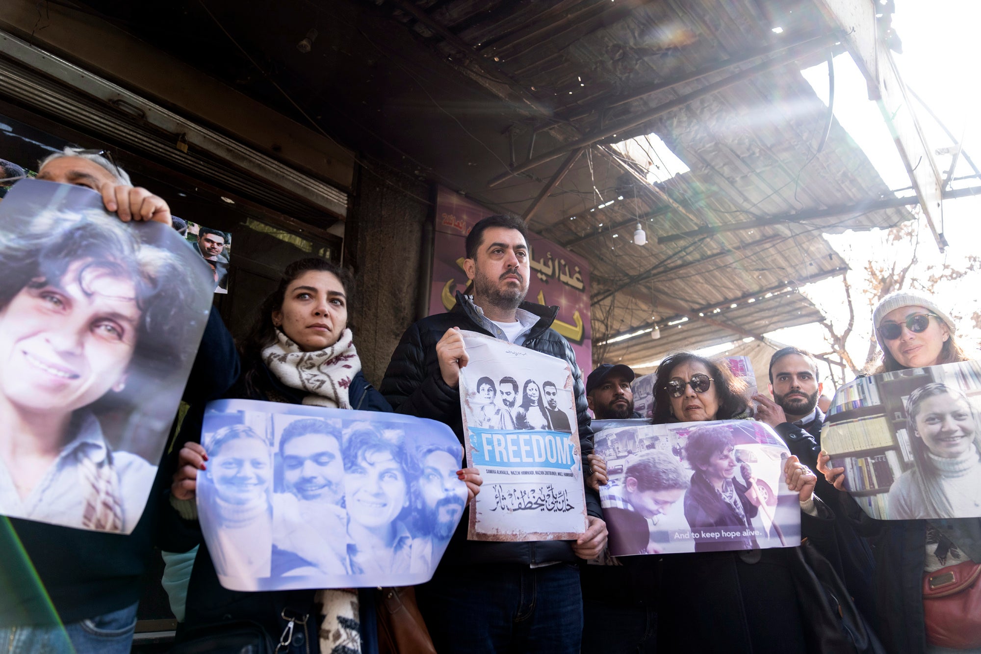 People hold photos and protest signs at a demonstration