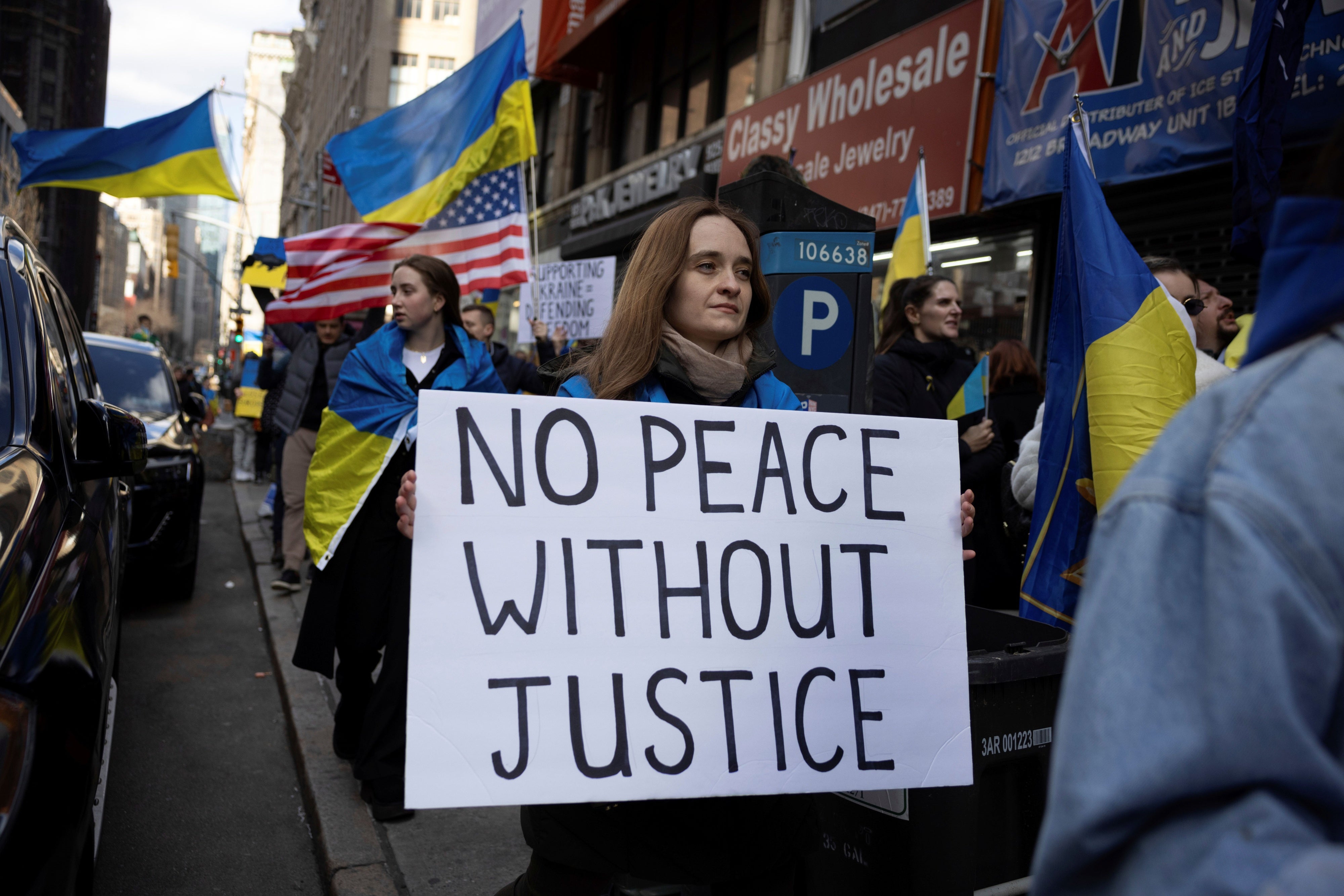 A demonstrator holds a sign that reads "No Peace Without Justice" at a protest