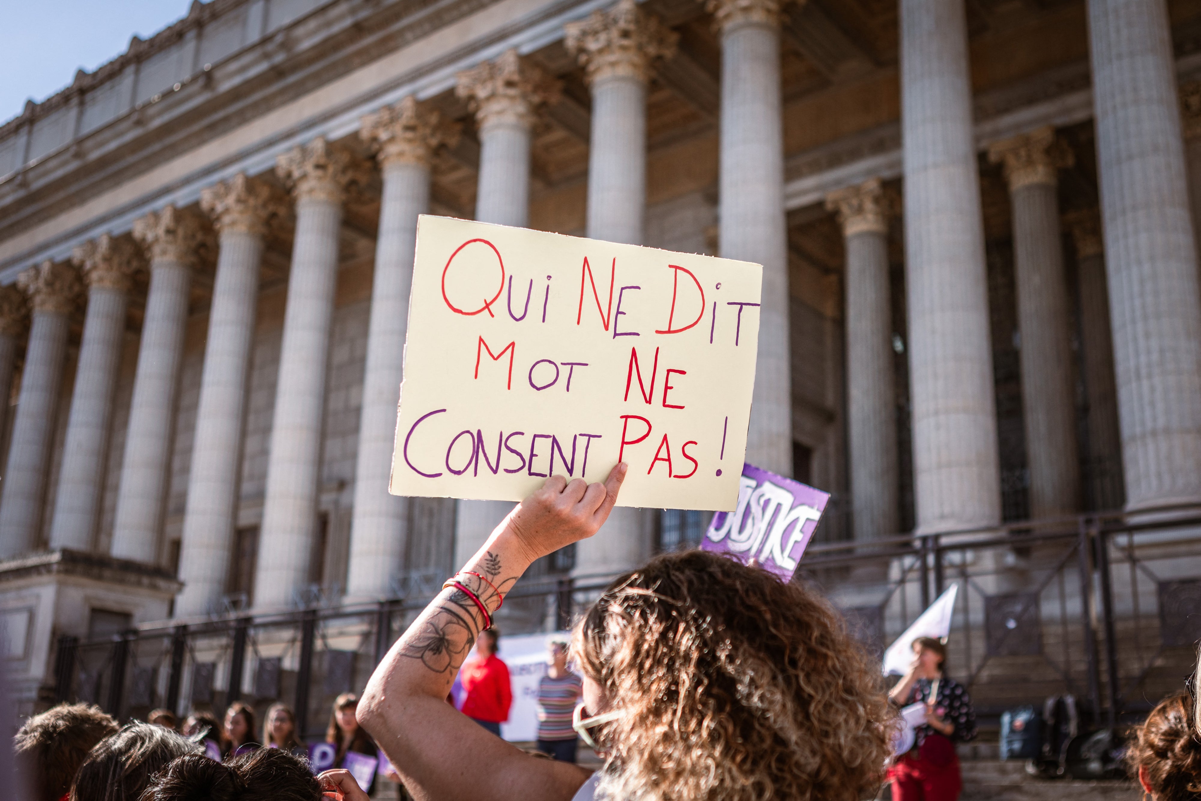An individual holding a sign saying “Who says words does not consent”  in front of the Palais de Justice during a rally in support of all victims of gender and sexual violence in Lyon, France, October 19, 2024.