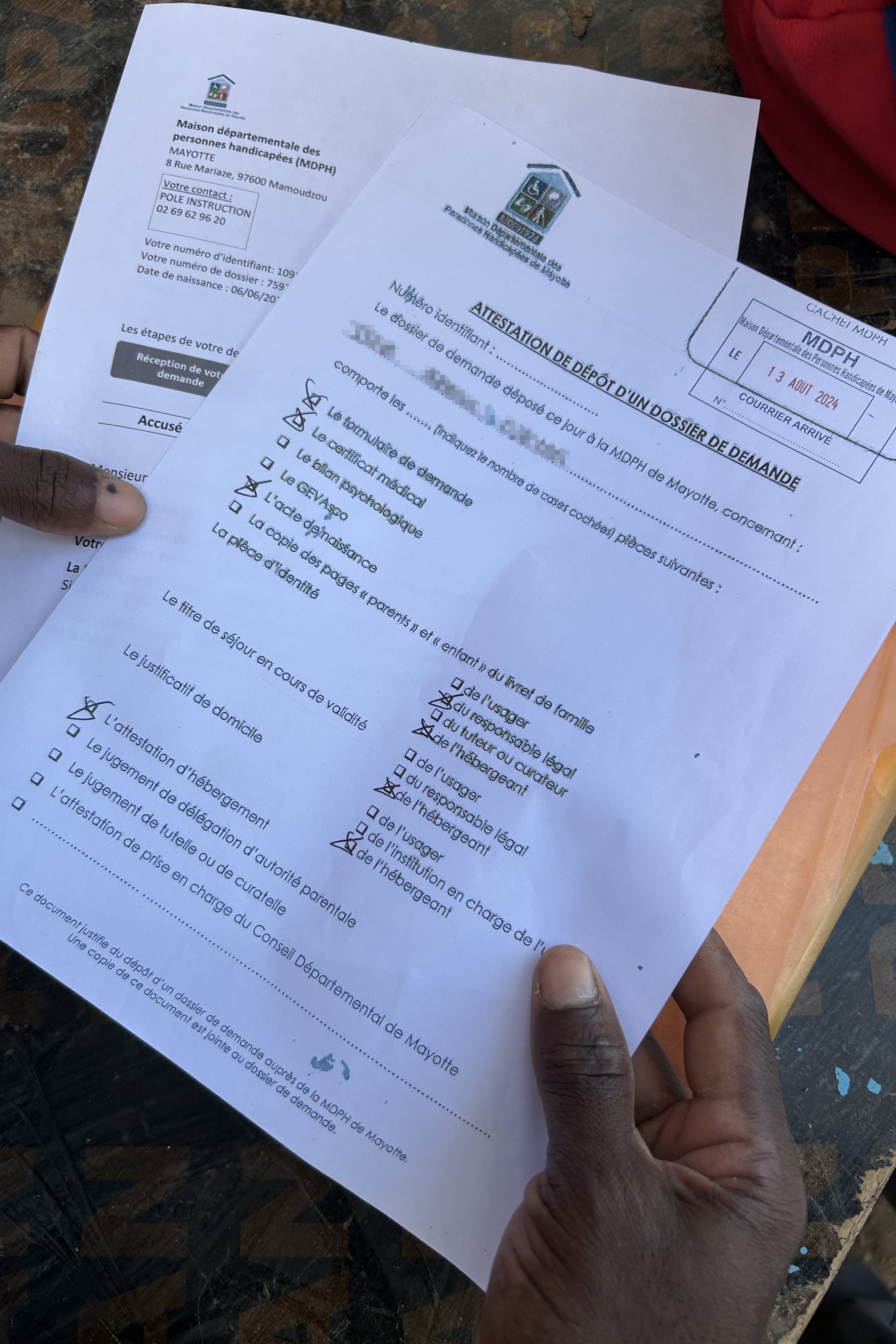 A man holds paperwork with names redacted