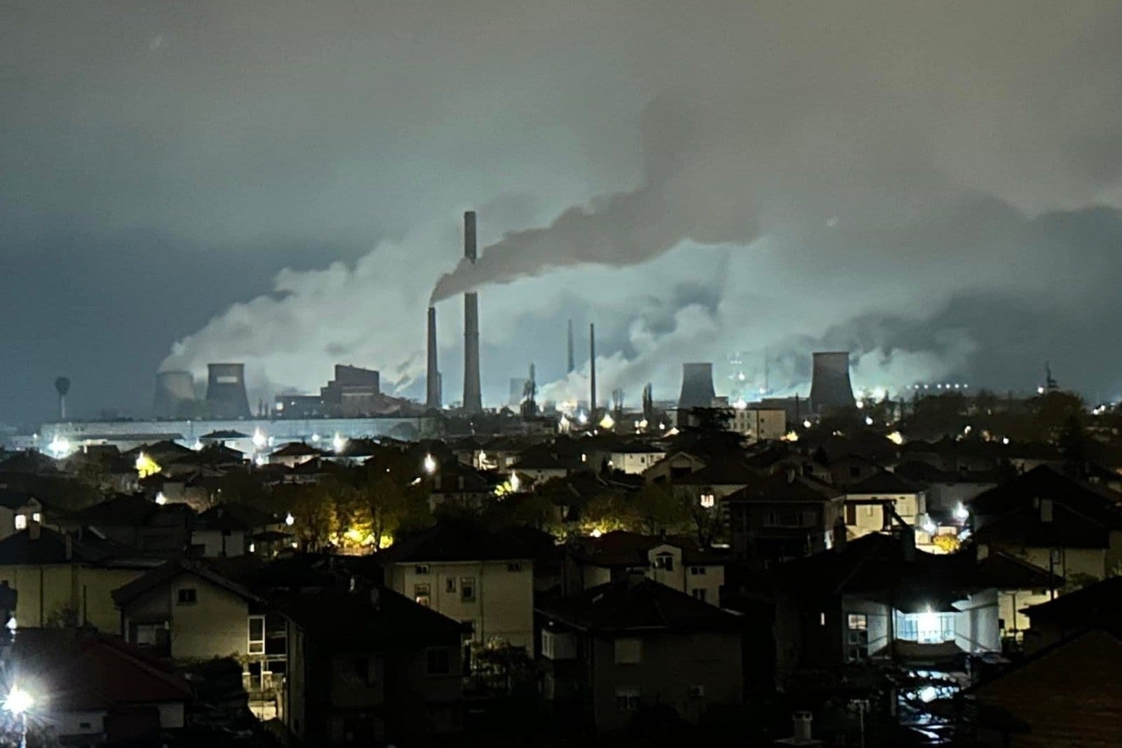 Smoke billowing from towers at a coal plant near a residential neighborhood