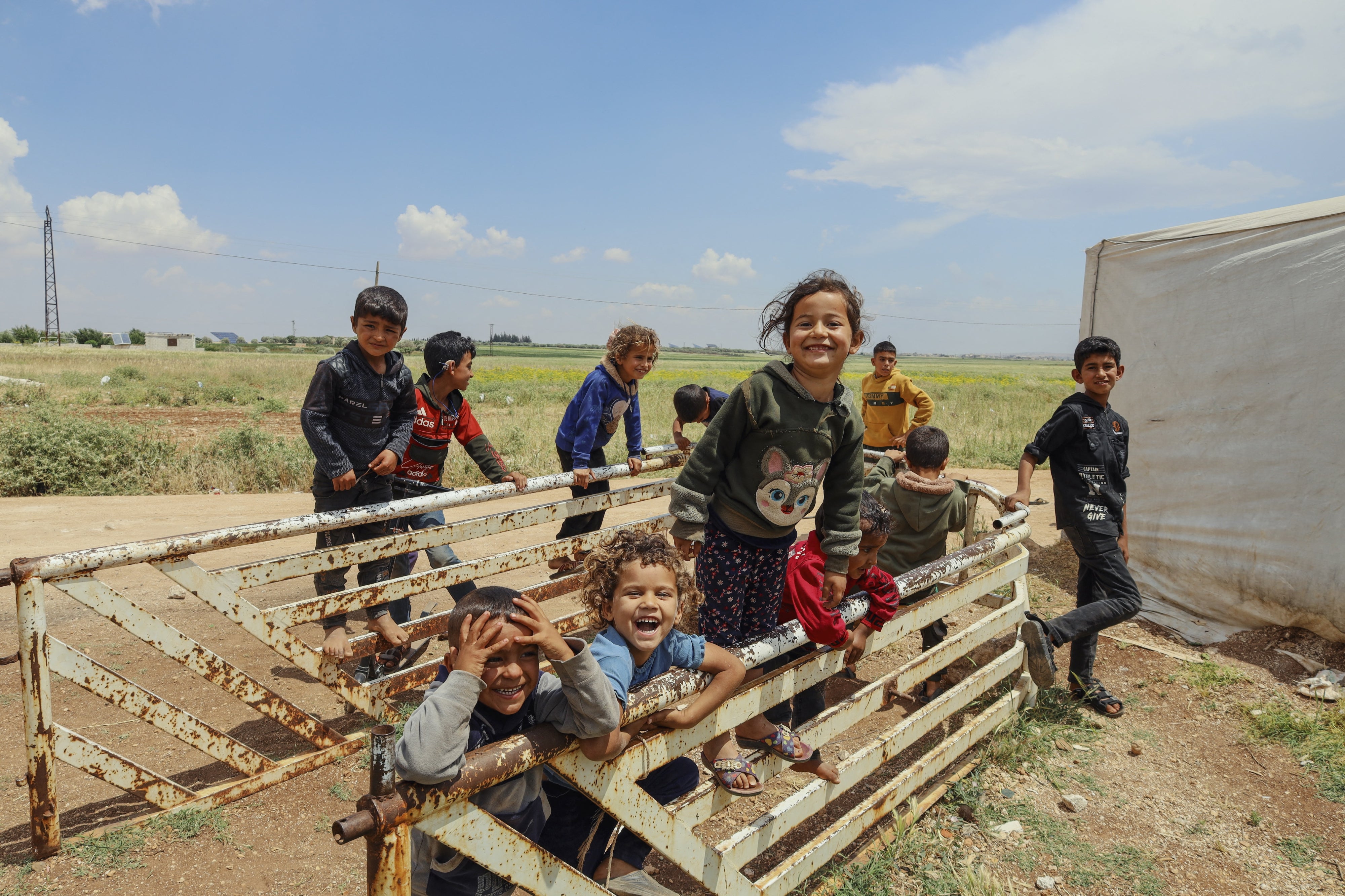 Displaced Syrian children laugh and play among temporary tents set up after the fall of the Bashar al-Assad government near Idlib, Syria, May 15, 2025.
