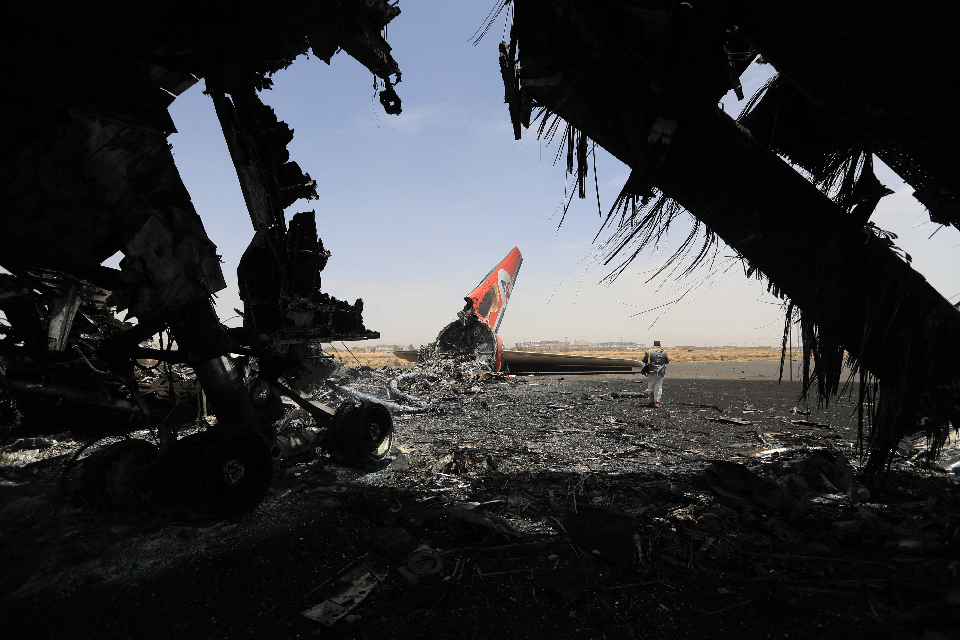 A Houthi rebel next to a destroyed plane at the Sanaa International Airport on May 7, 2025, a day after Israel's military warplanes struck Yemen's rebel-held capital Sanaa. 