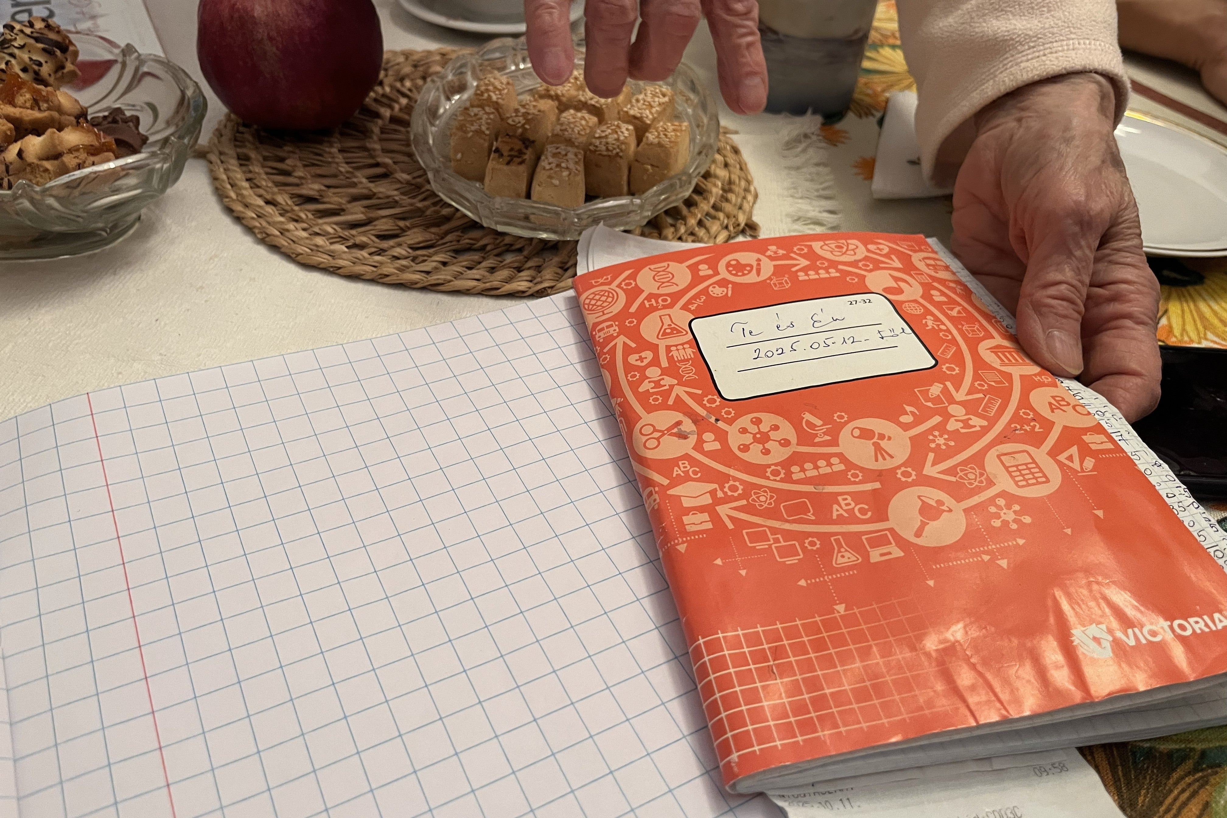 Anna, 80, shows a notebook containing detailed records of monthly expenses, for herself and her sister Erika, 84, in their home in Budapest, Hungary, October 2025.