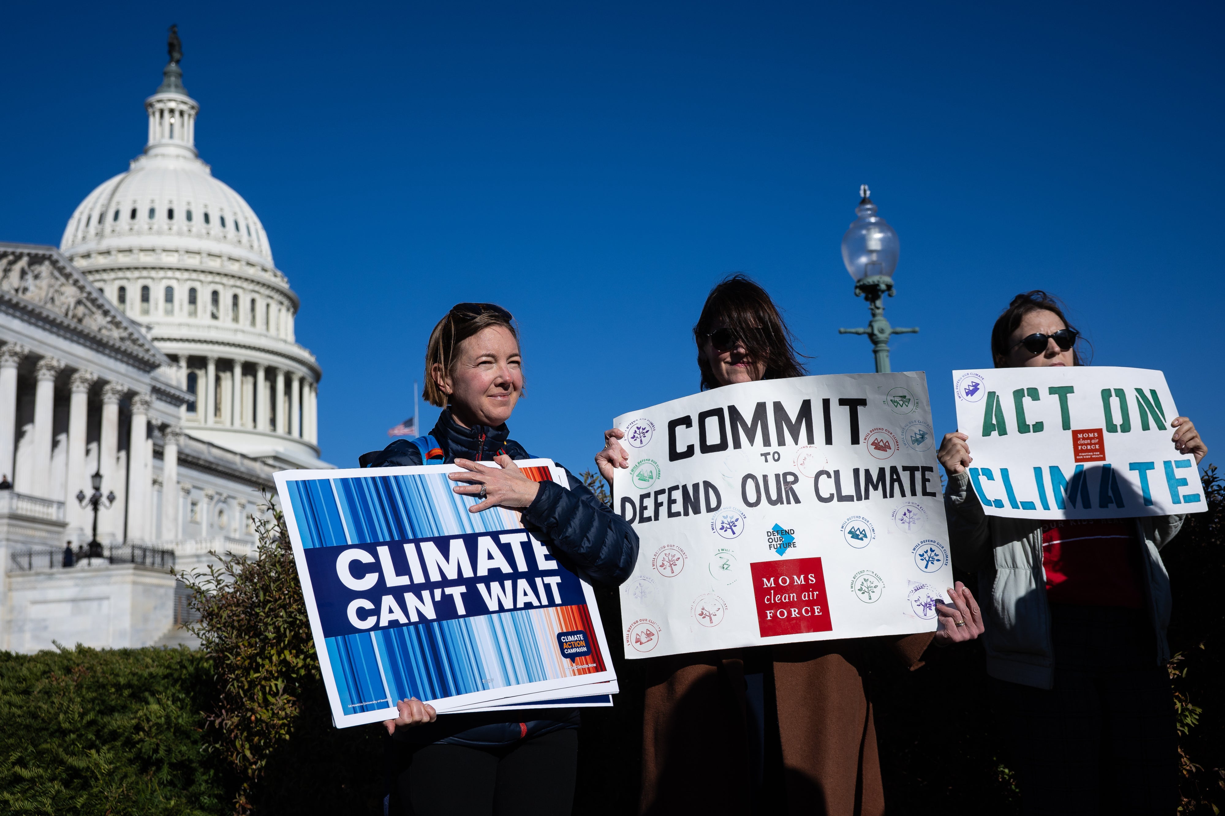 Climate activists hold signs during a press conference outside the US capitol building