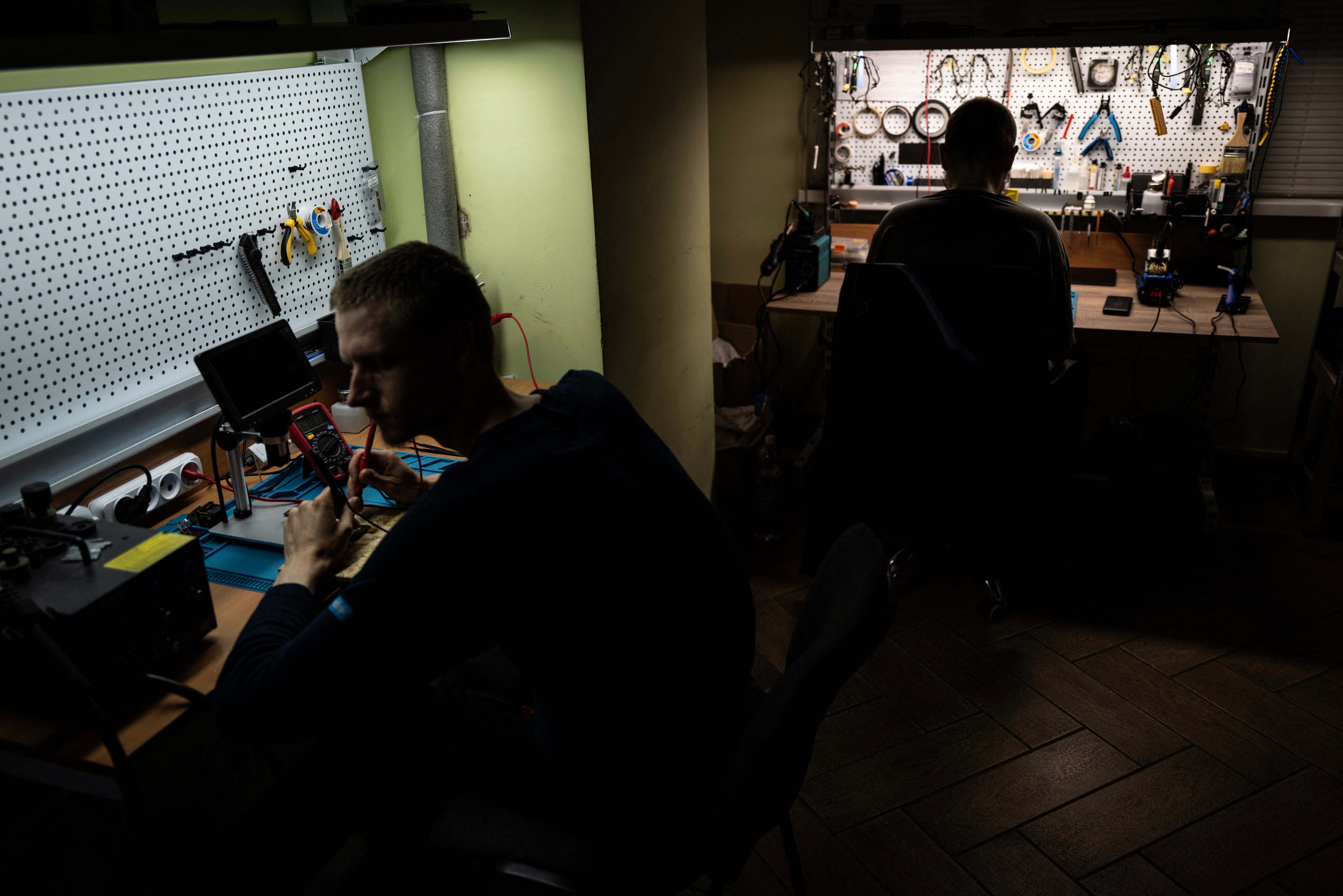 Two Ukrainian soldiers work in a drone workshop in an undisclosed location near the Russian border in the Kursk region, on June 12, 2025.