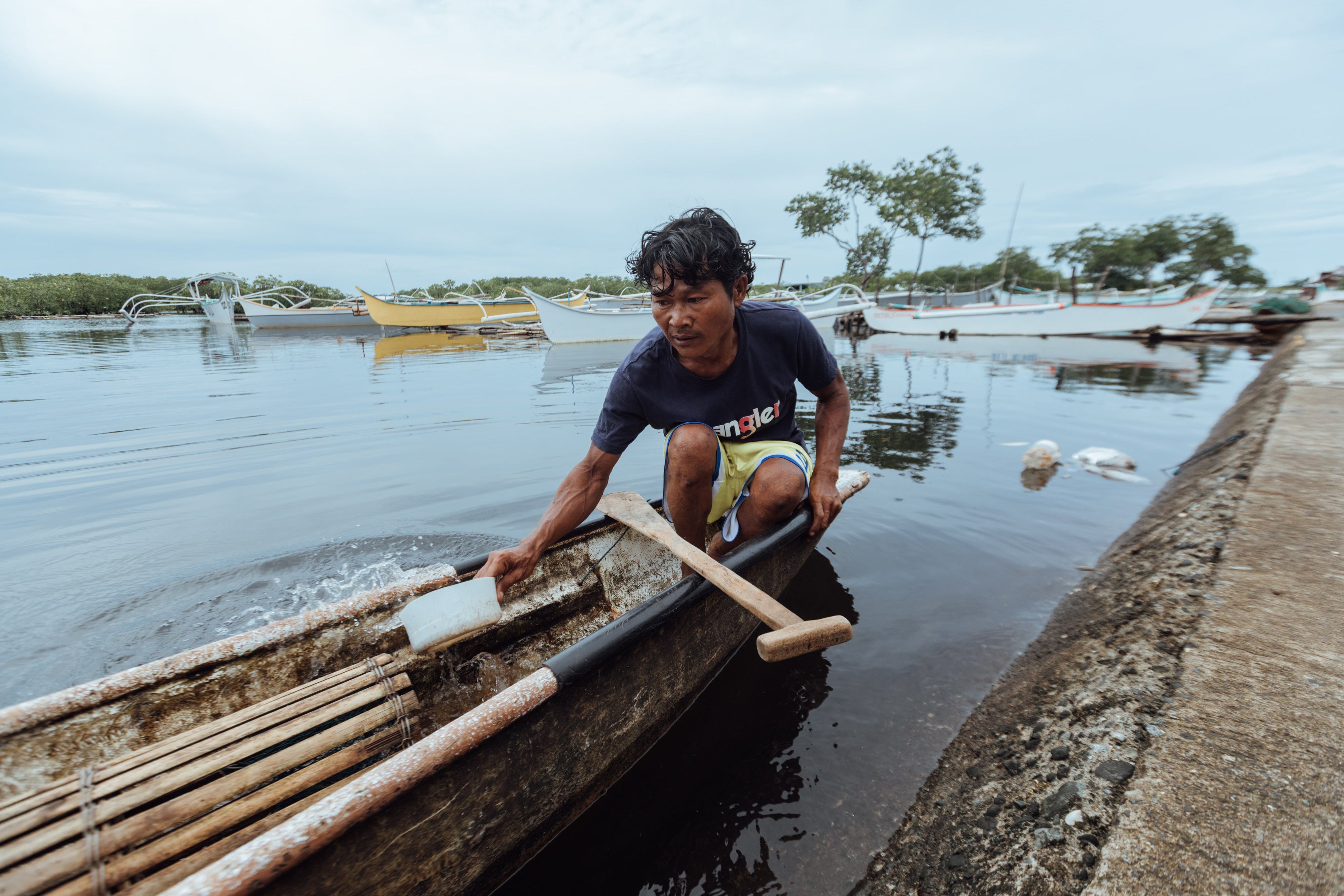 Hasael Compra who has a physical disability, removing water from his fishing boat in Del Carmen, Siargao, Philippines, 2025.