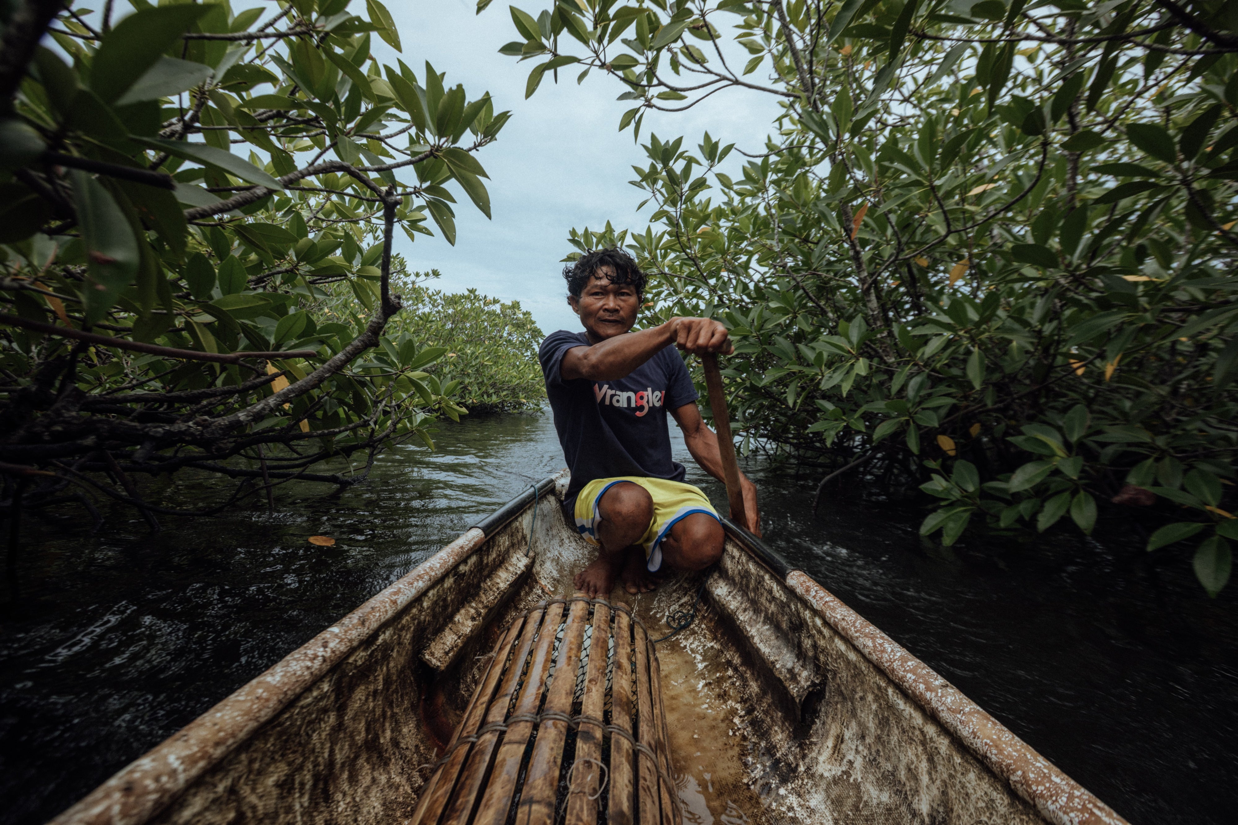 Hasael on his fishing boat moving through a mangrove forest in Siargao, Philippines, 2025.