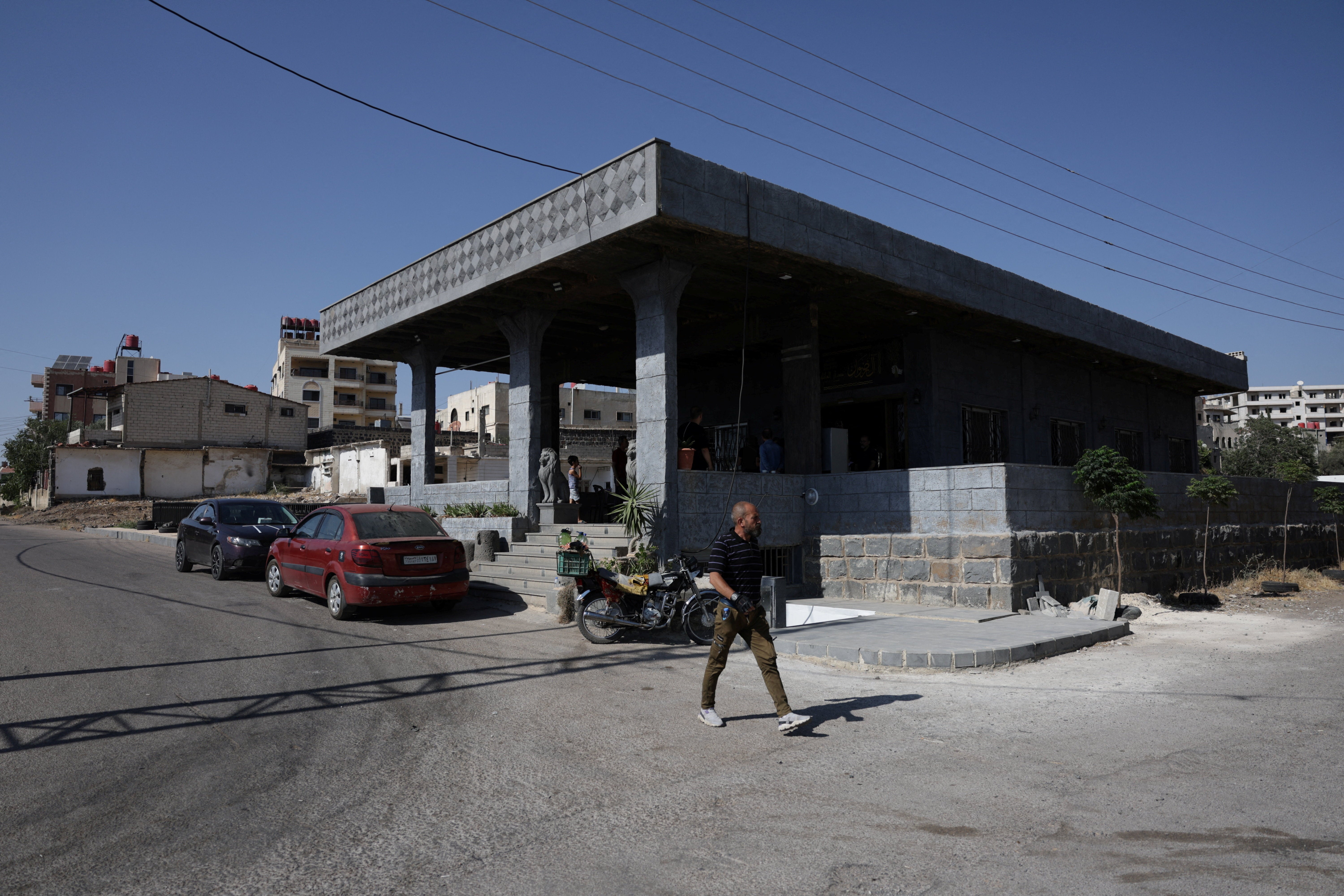 A person walks past the Al-Radwan guest house, where a deadly shooting occurred, in the predominantly Druze city of Sweida, Syria, July 25, 2025. 
