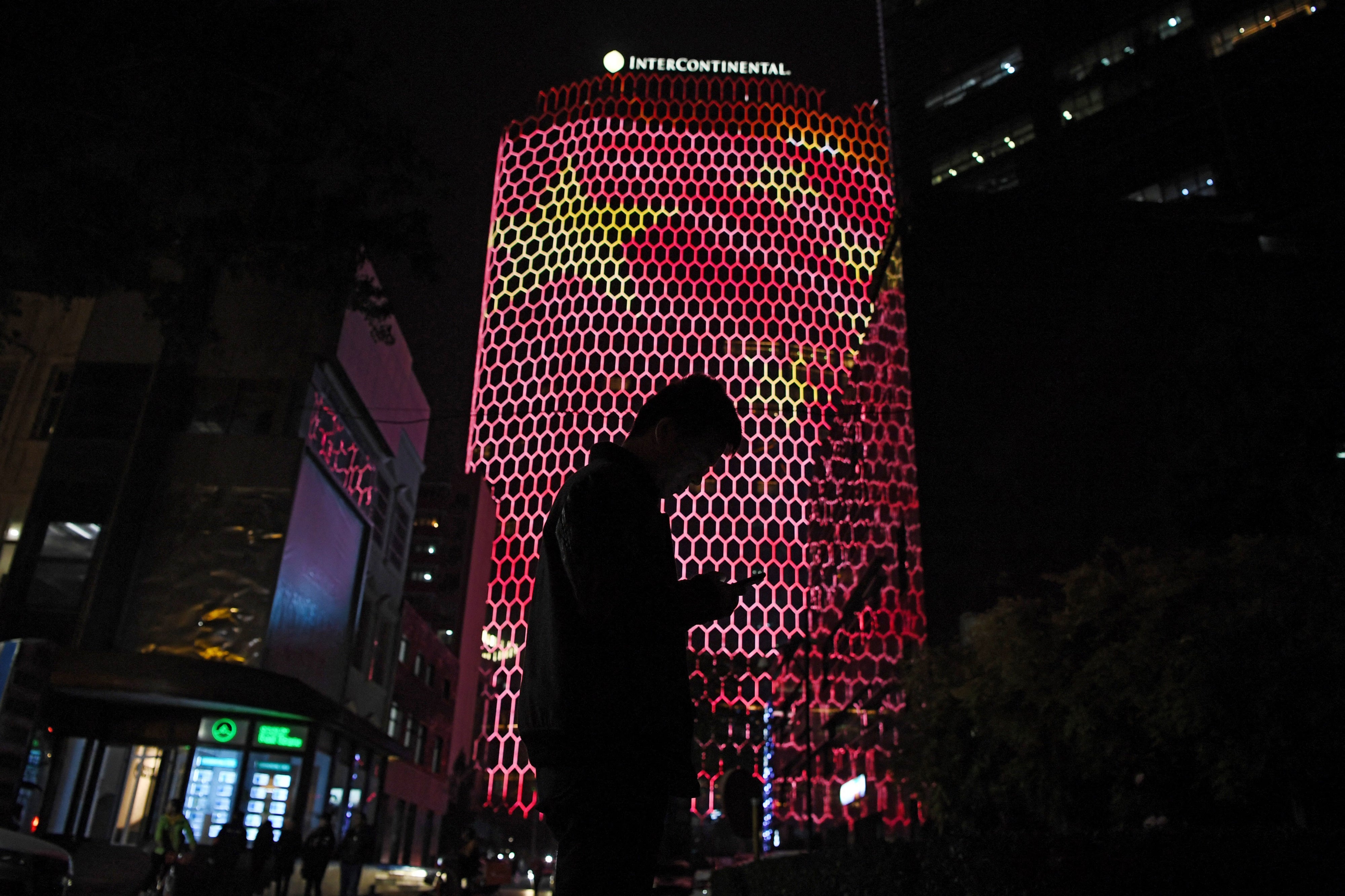 A person standing before an image of the Chinese national flag in Beijing, October 23, 2017. 