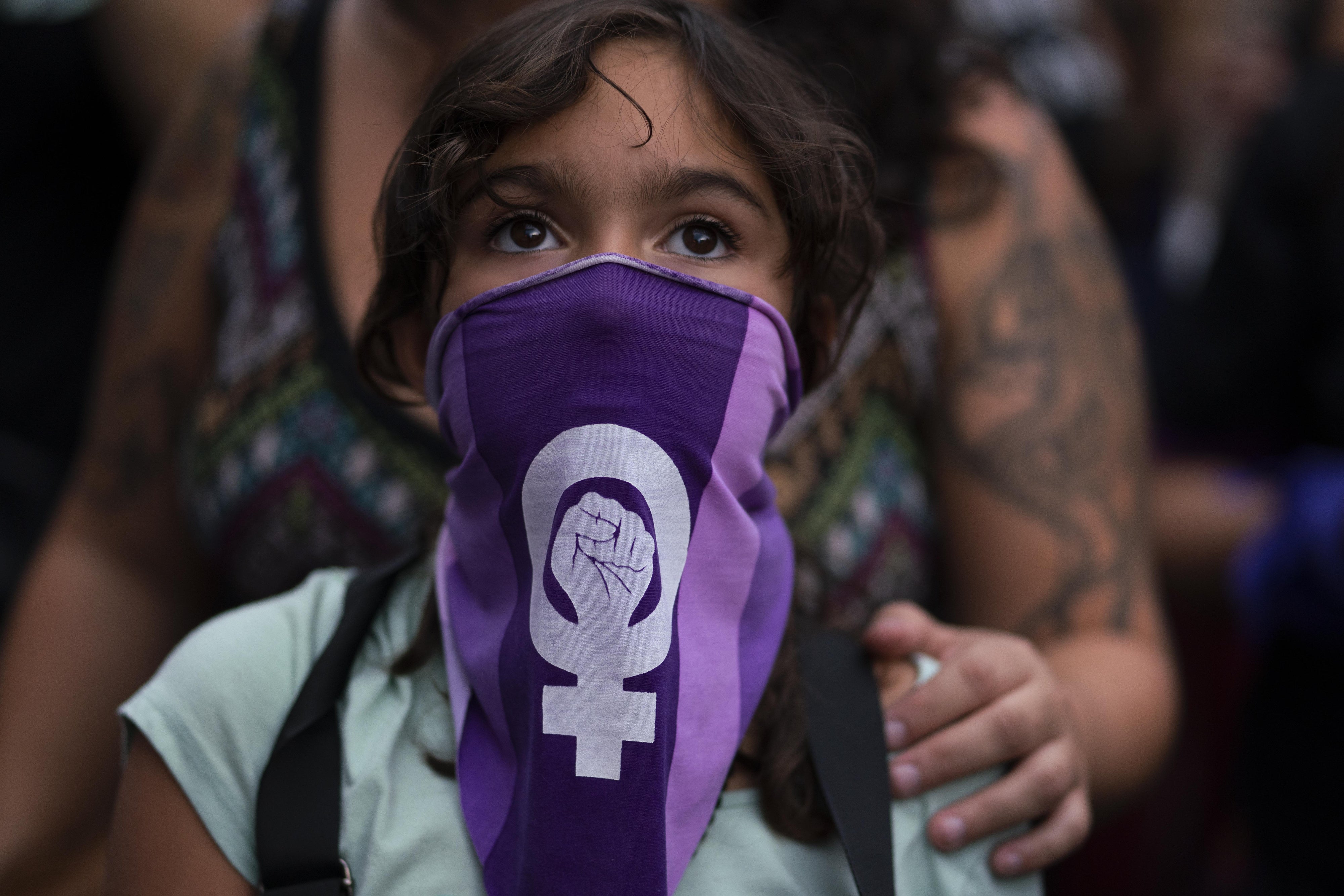 A girl wearing a purple face bandana at a march