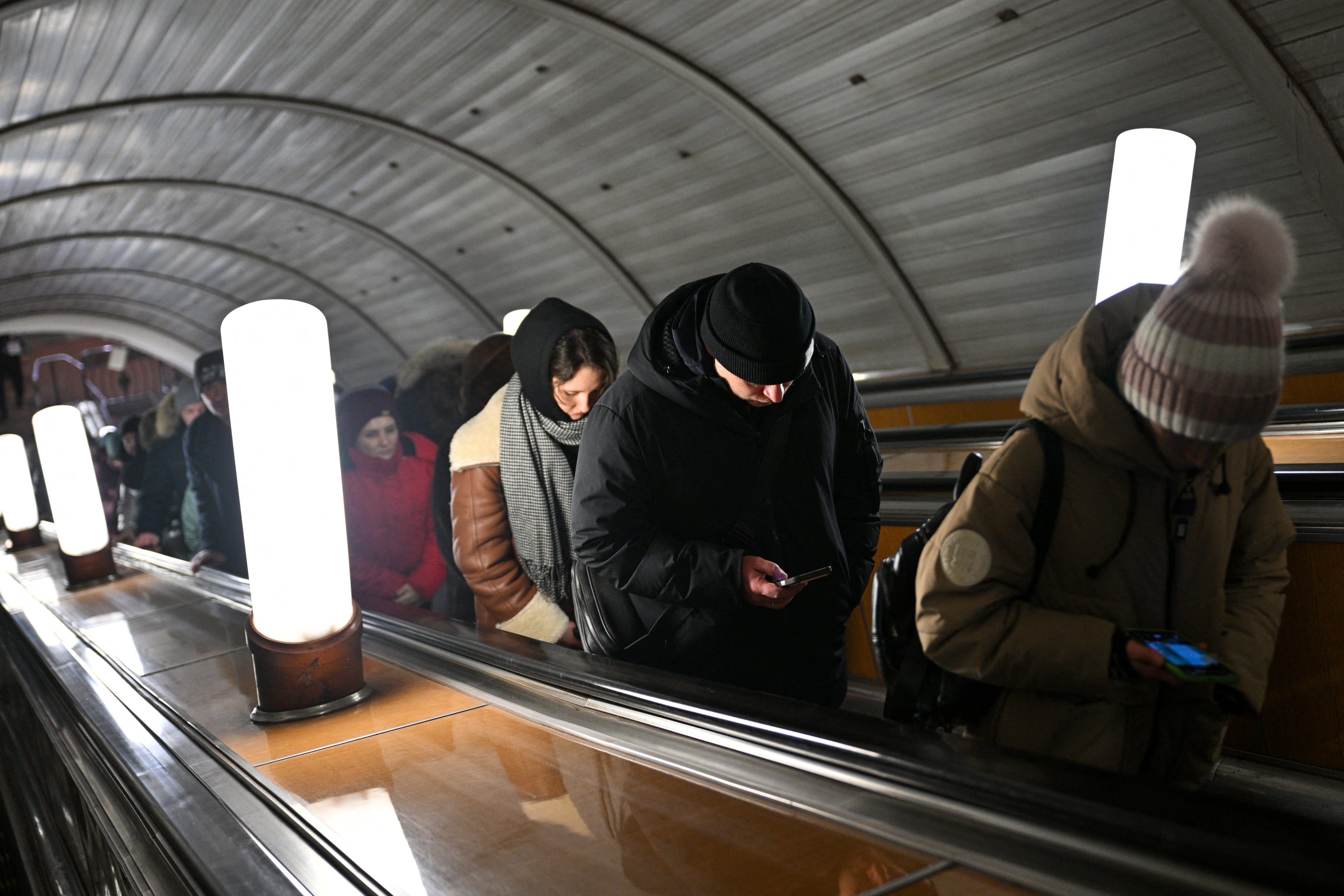 People use their smartphones while riding an escalator in the Moscow metro, Russia, on February 12, 2026.