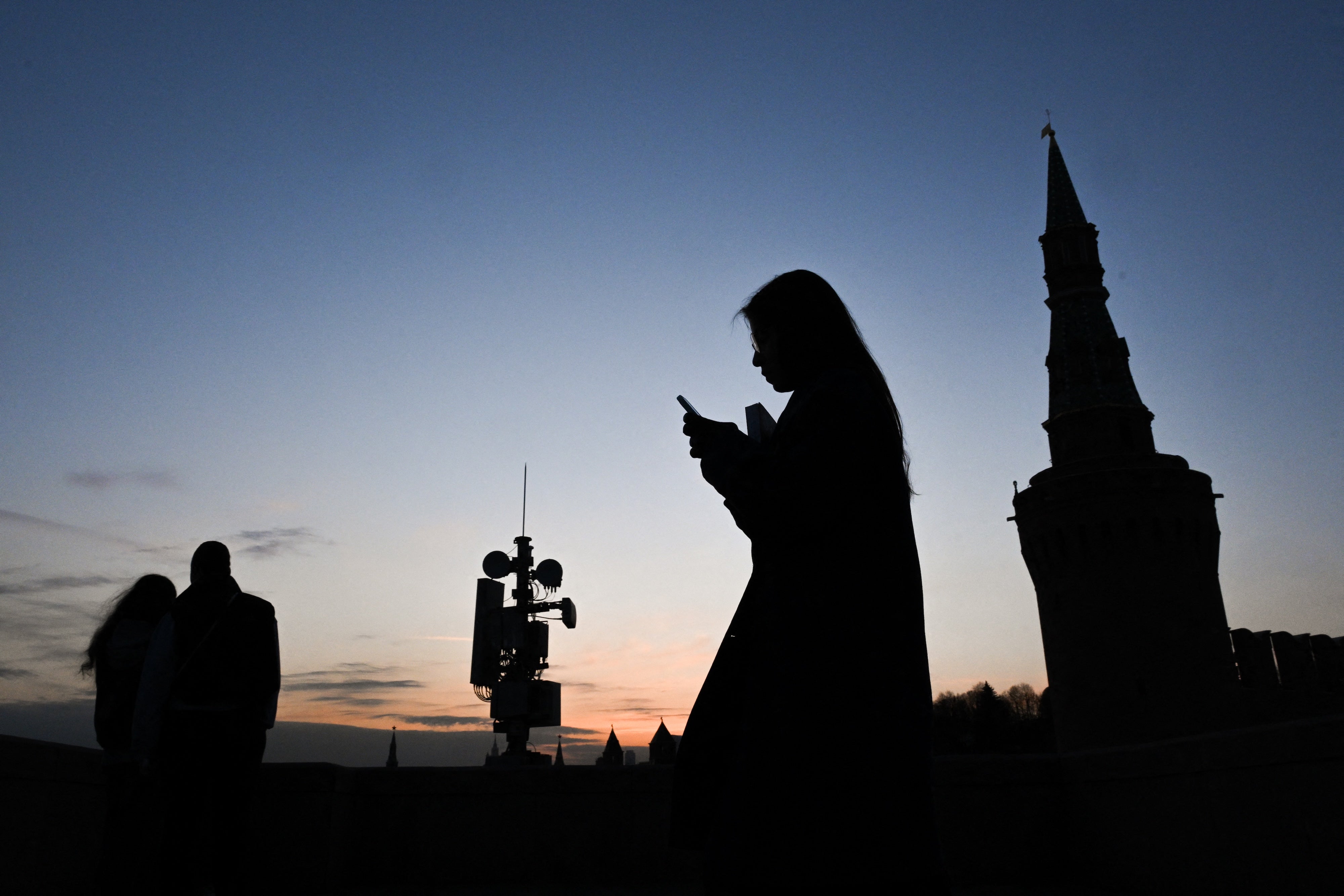 A person uses their smartphone as they walk on the Moskvoretsky bridge in Moscow, Russia, March 17, 2026. 