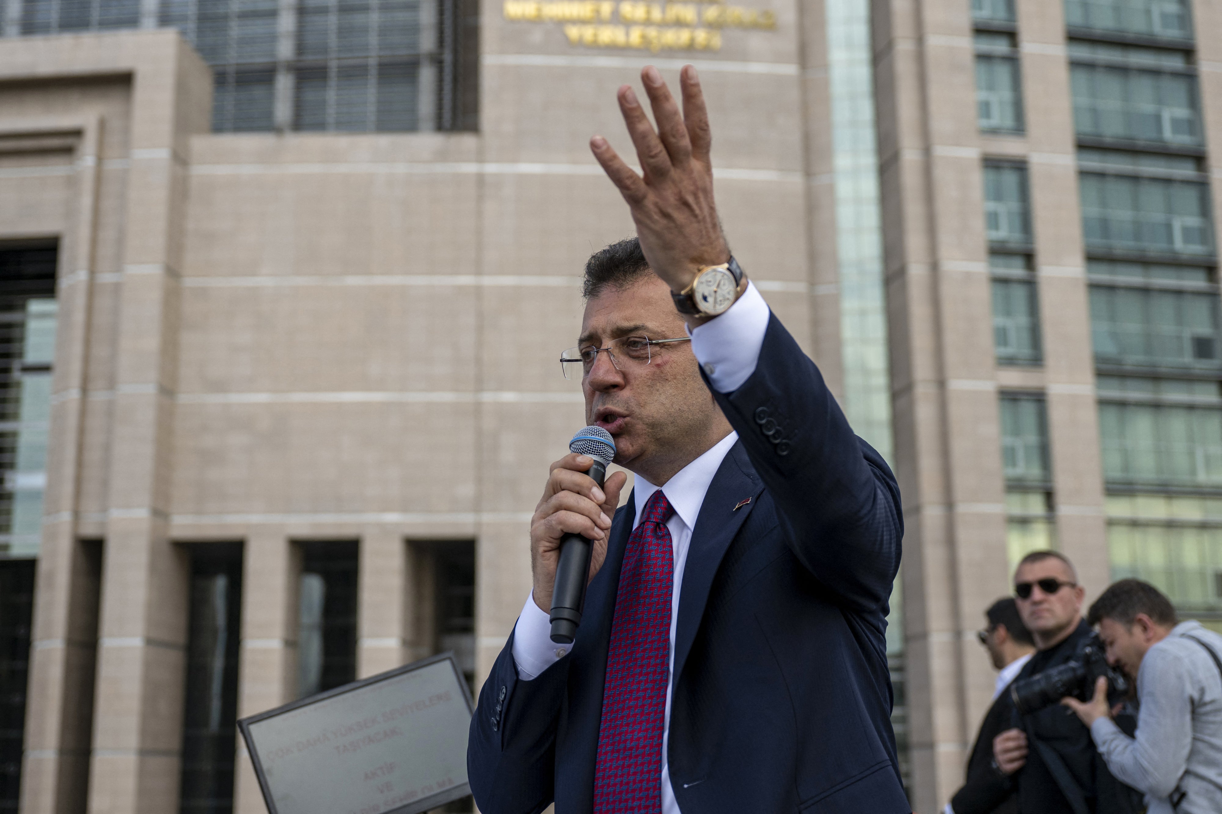 A man speaking into a microphone in front of a courthouse