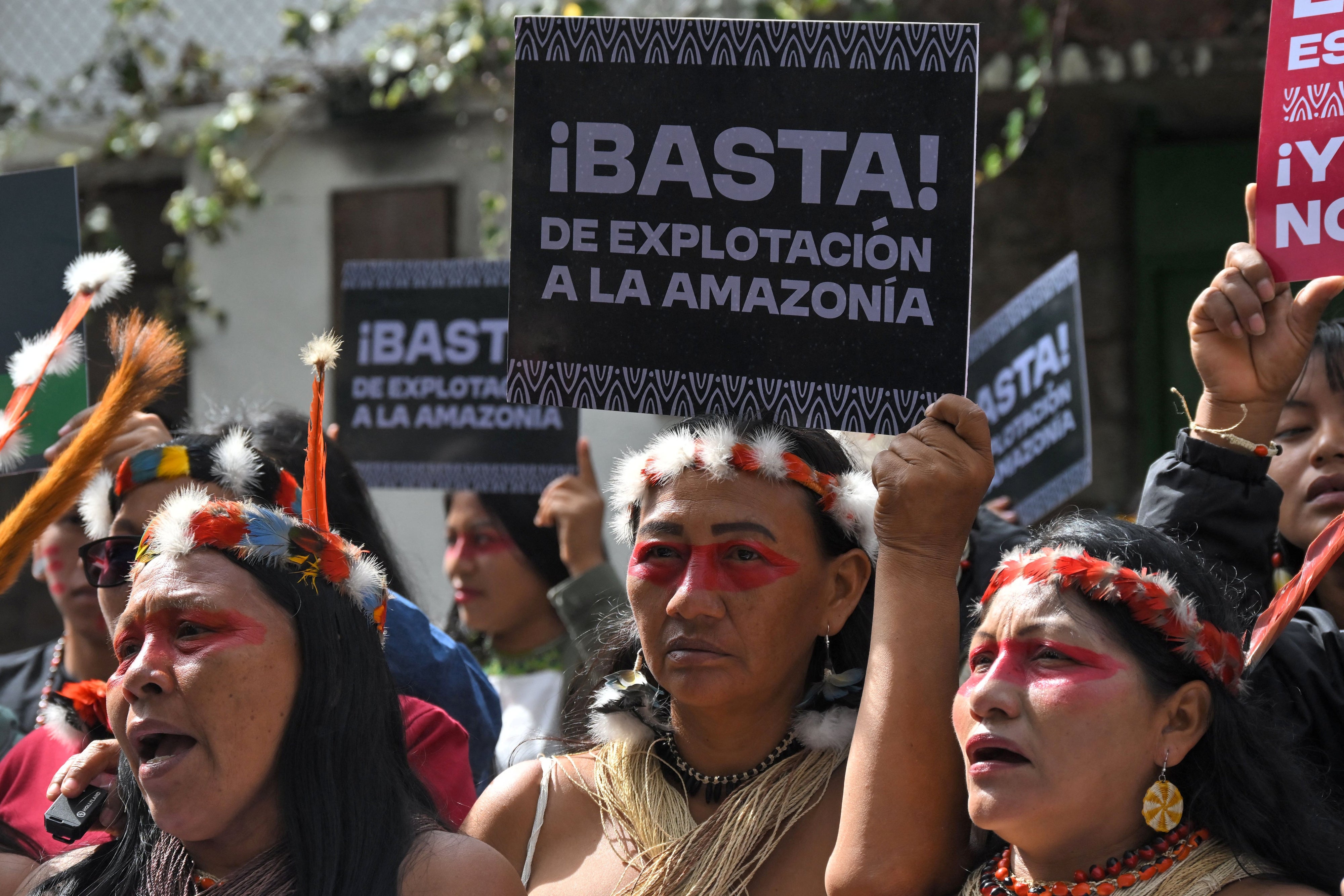 Indigenous women hold up placards in Spanish at a protest