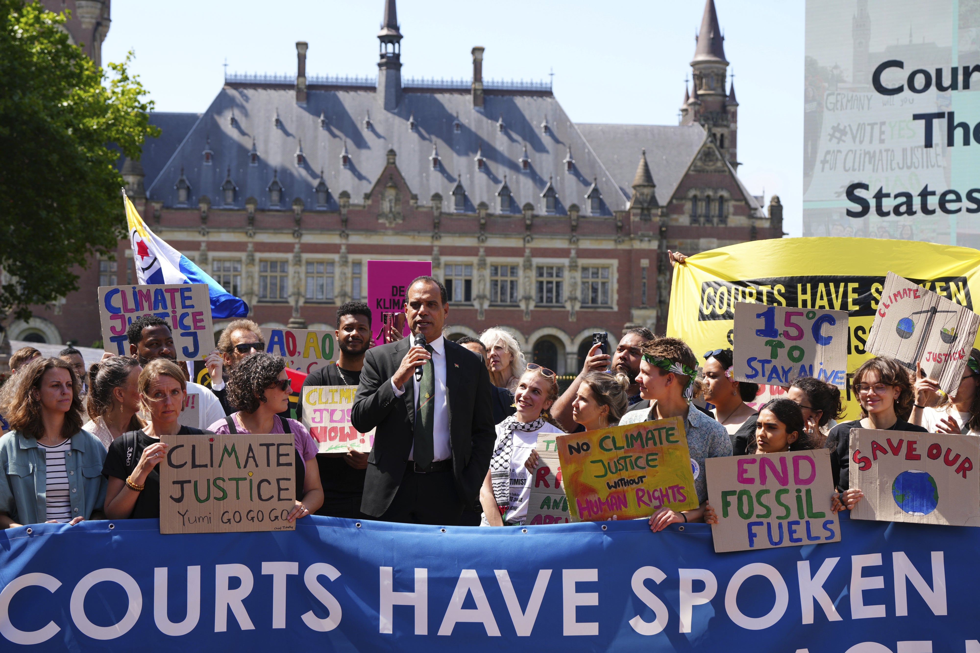 A man speaks during a demonstration with a banner that reads "Courts Have Spoken"
