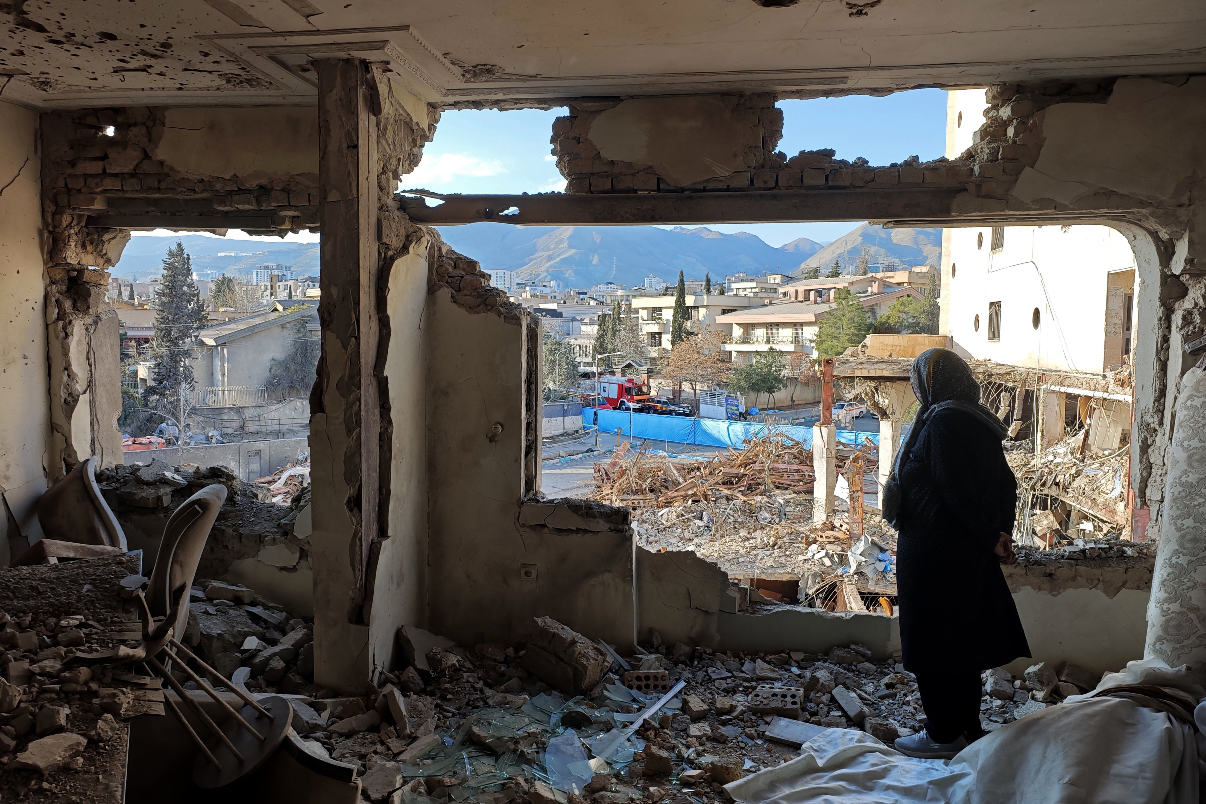 A woman looks out from her destroyed apartment in the Shahrak-e Gharb neighborhood of Tehran, Iran, March 21, 2026. 