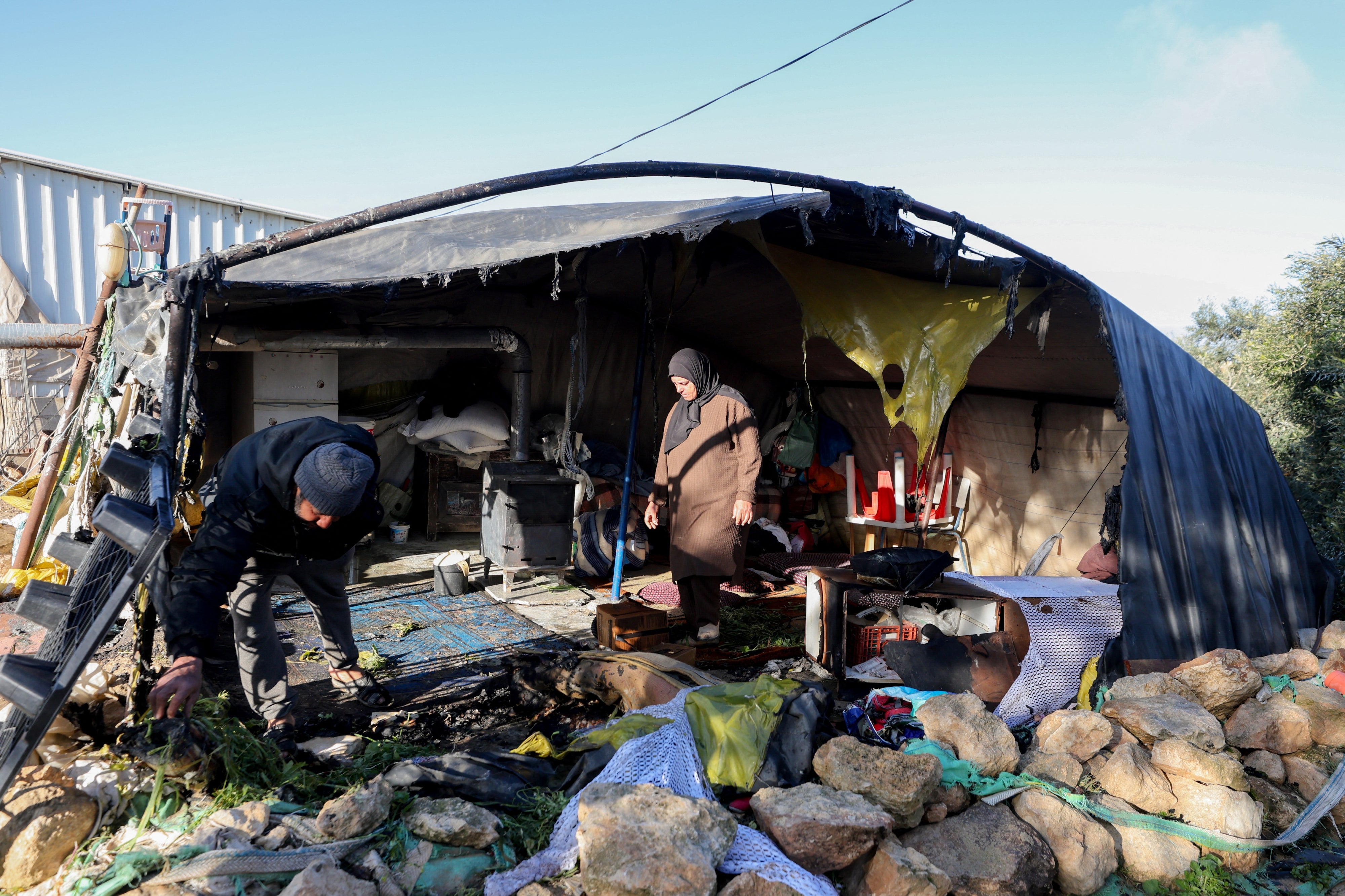 Residents inspect damaged belongings inside a tent burned by suspected Israeli settlers in the village of Susya in Masafer Yatta, south of Hebron, in the Israeli-occupied West Bank, February 25, 2026. 
