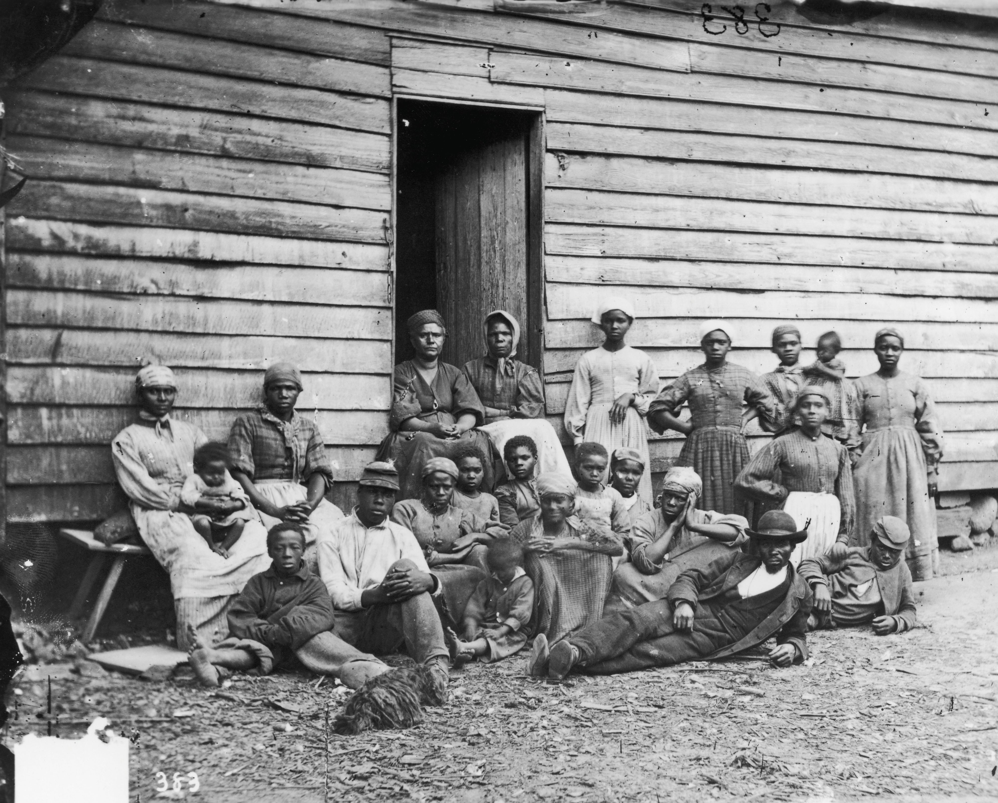 Formerly enslaved people sit at Foller's House in Cumberland Landing, Virginia, US, circa 1850.