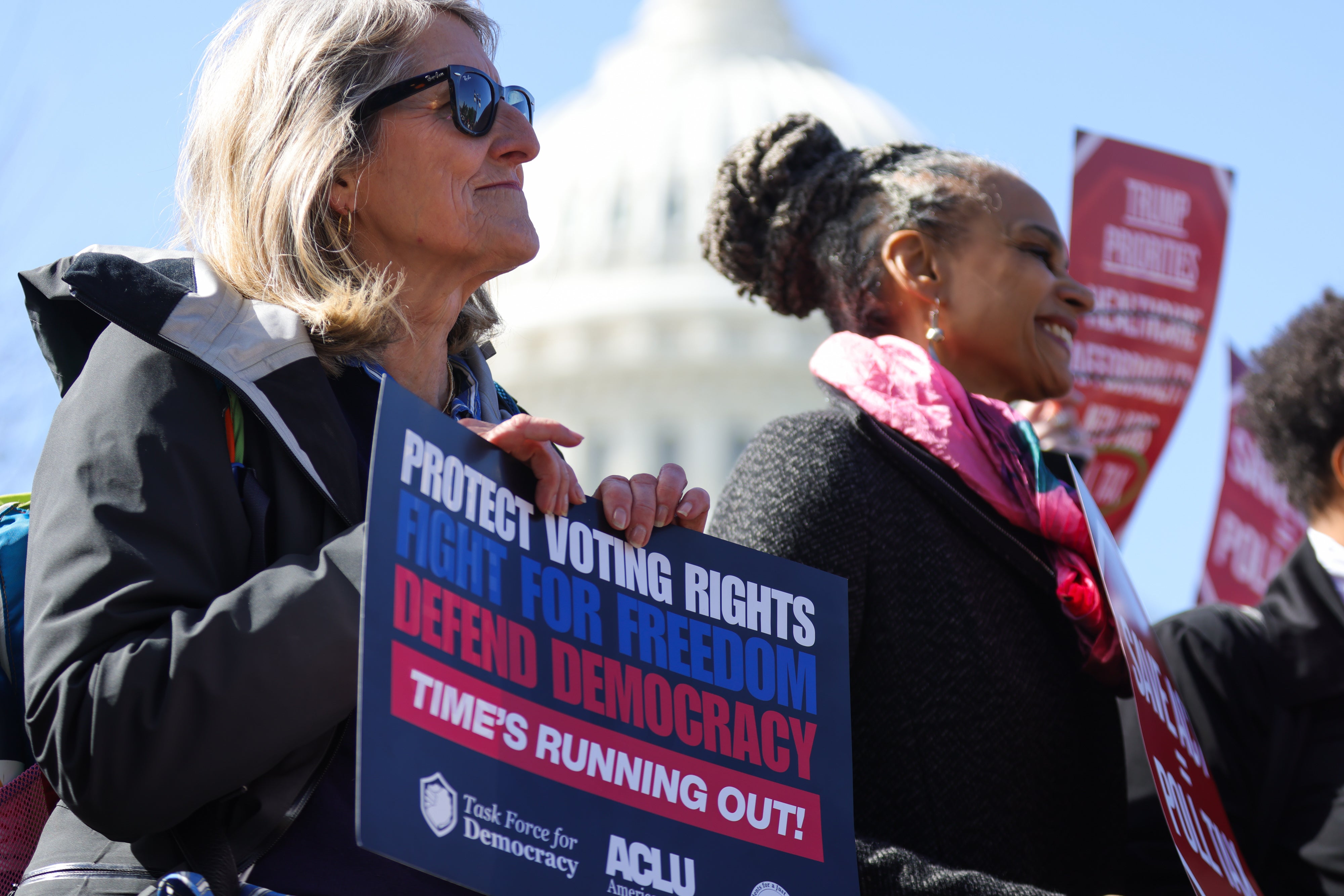 People hold signs at a rally and press conference against the SAVE America Act at the US Capitol in Washington, DC, on March 18, 2026.