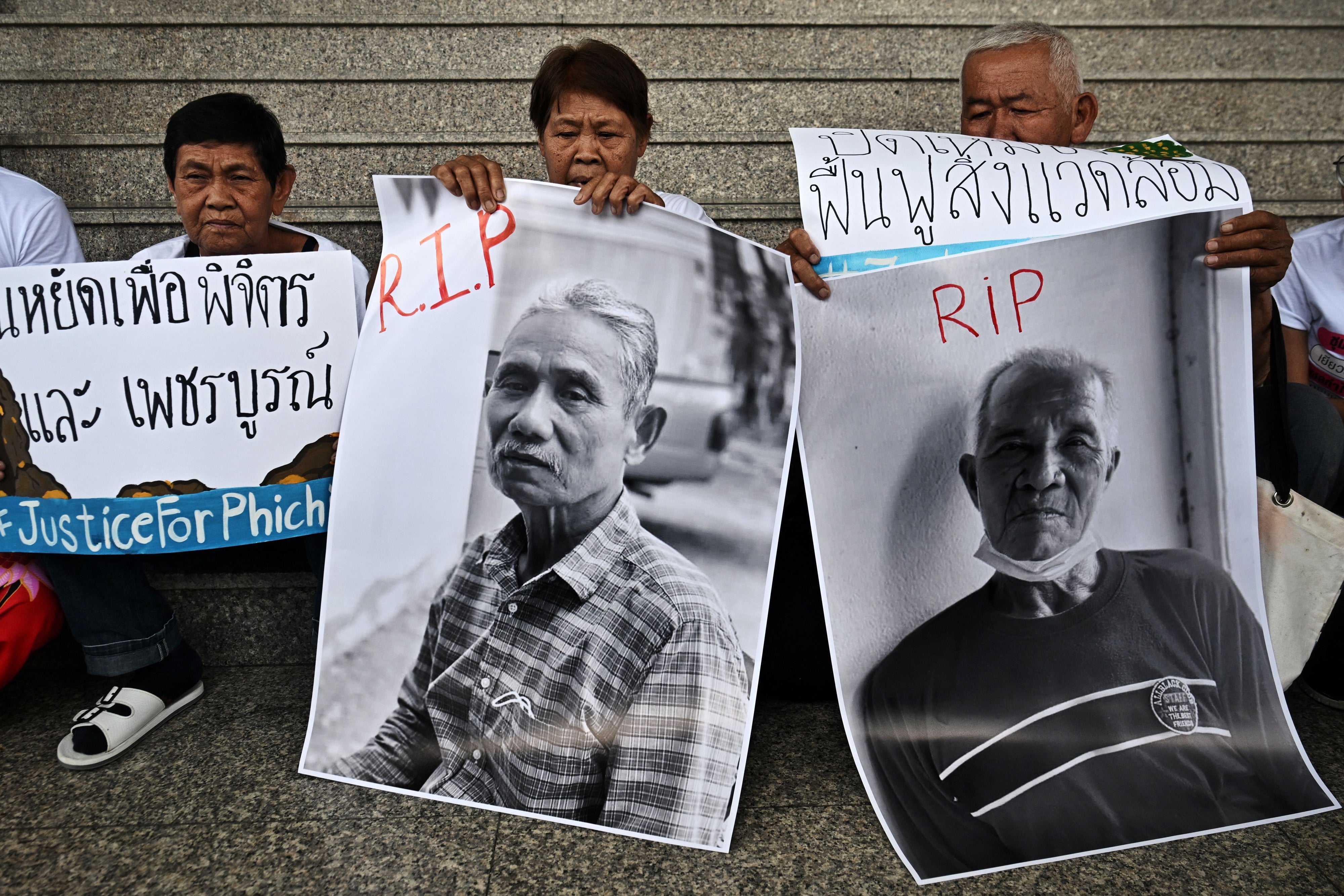 People hold photos and placards outside of a courthouse