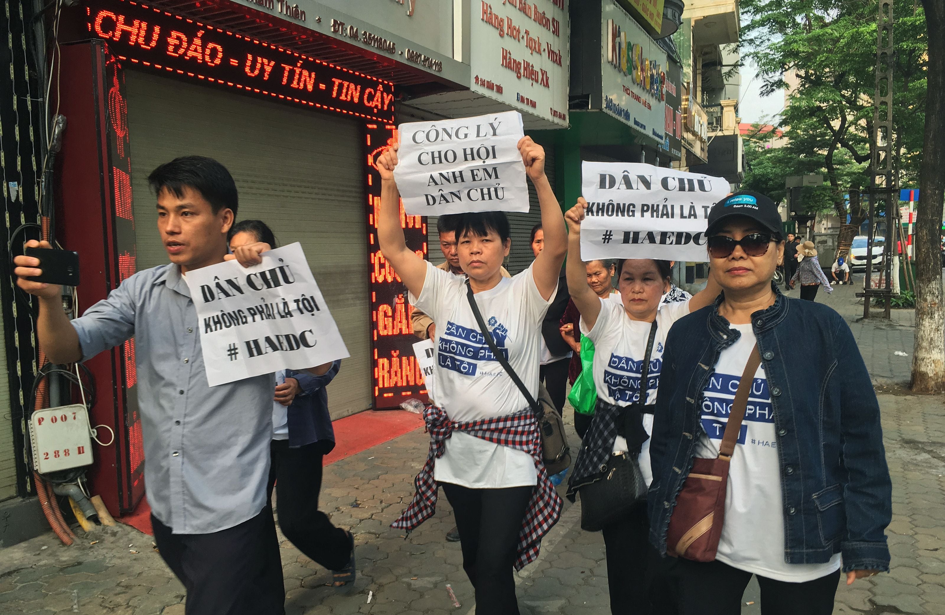 Protesters, including Can Thi Theu and Trinh Ba Tu, display placards as they march towards a courthouse during the trial of the prominent lawyer Nguyen Van Dai and five other activists in Hanoi, Vietnam, on April 5, 2018.