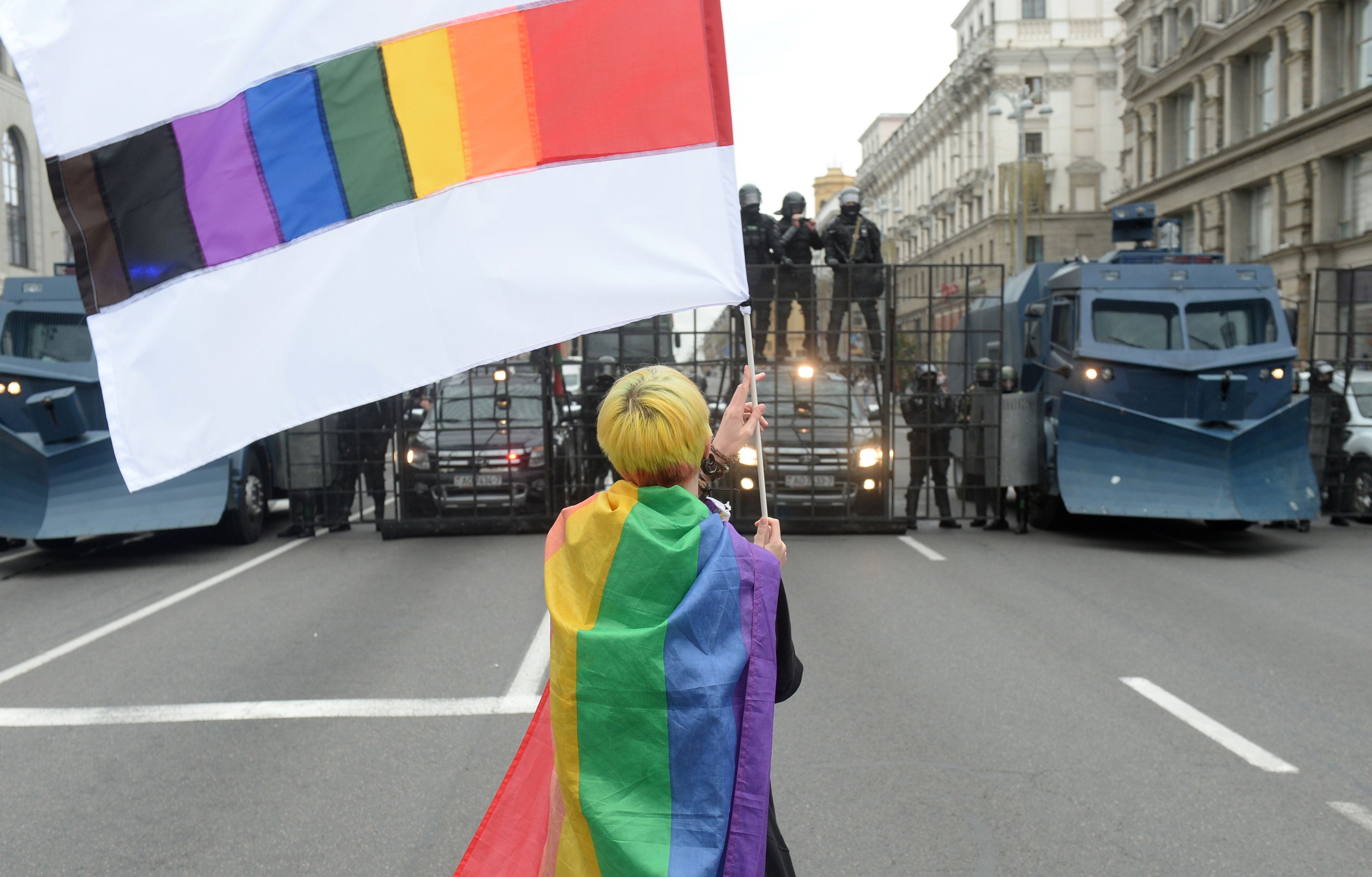 An activist waves a rainbow flag in front of a line of police