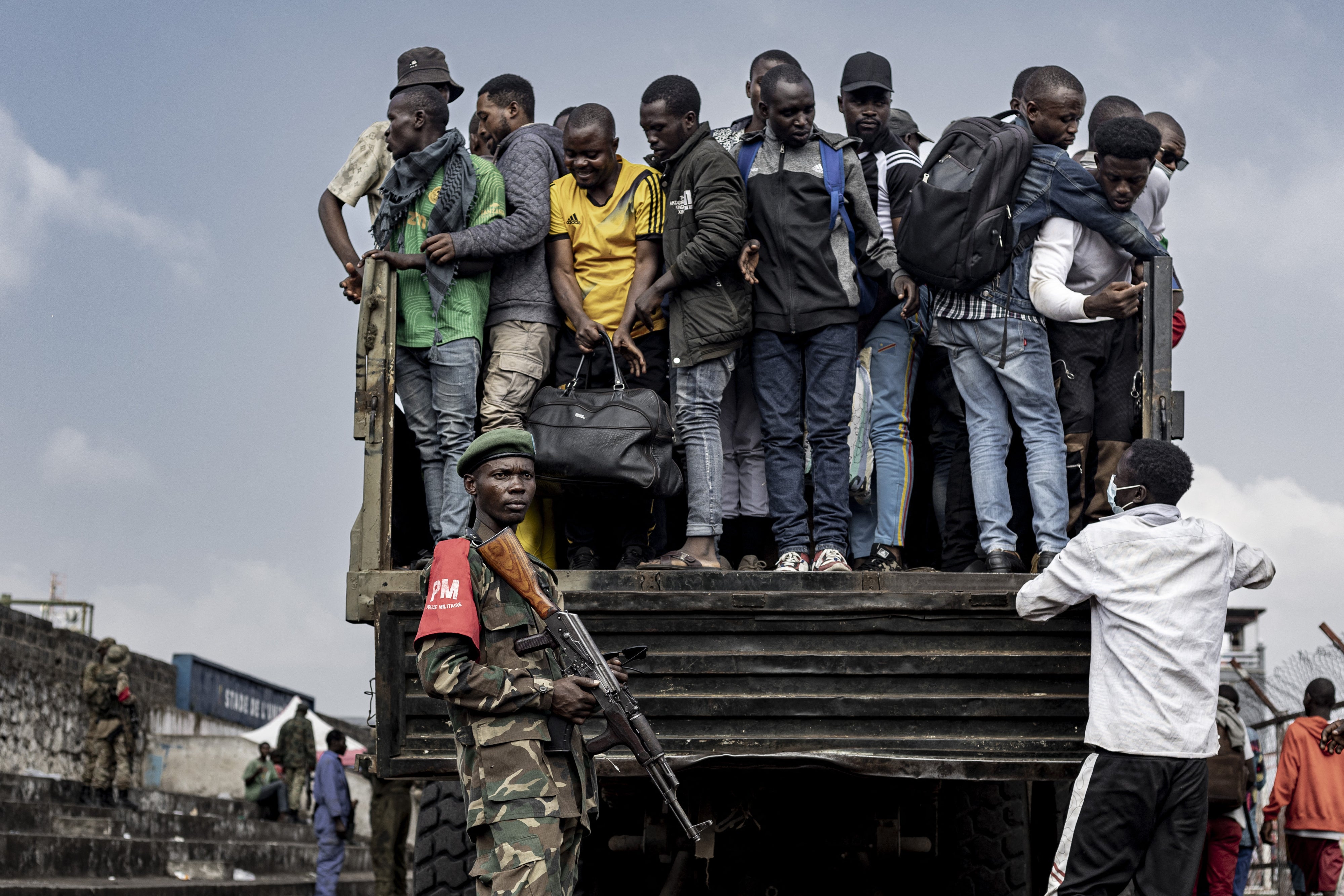 M23 fighters stand guard as people board a truck