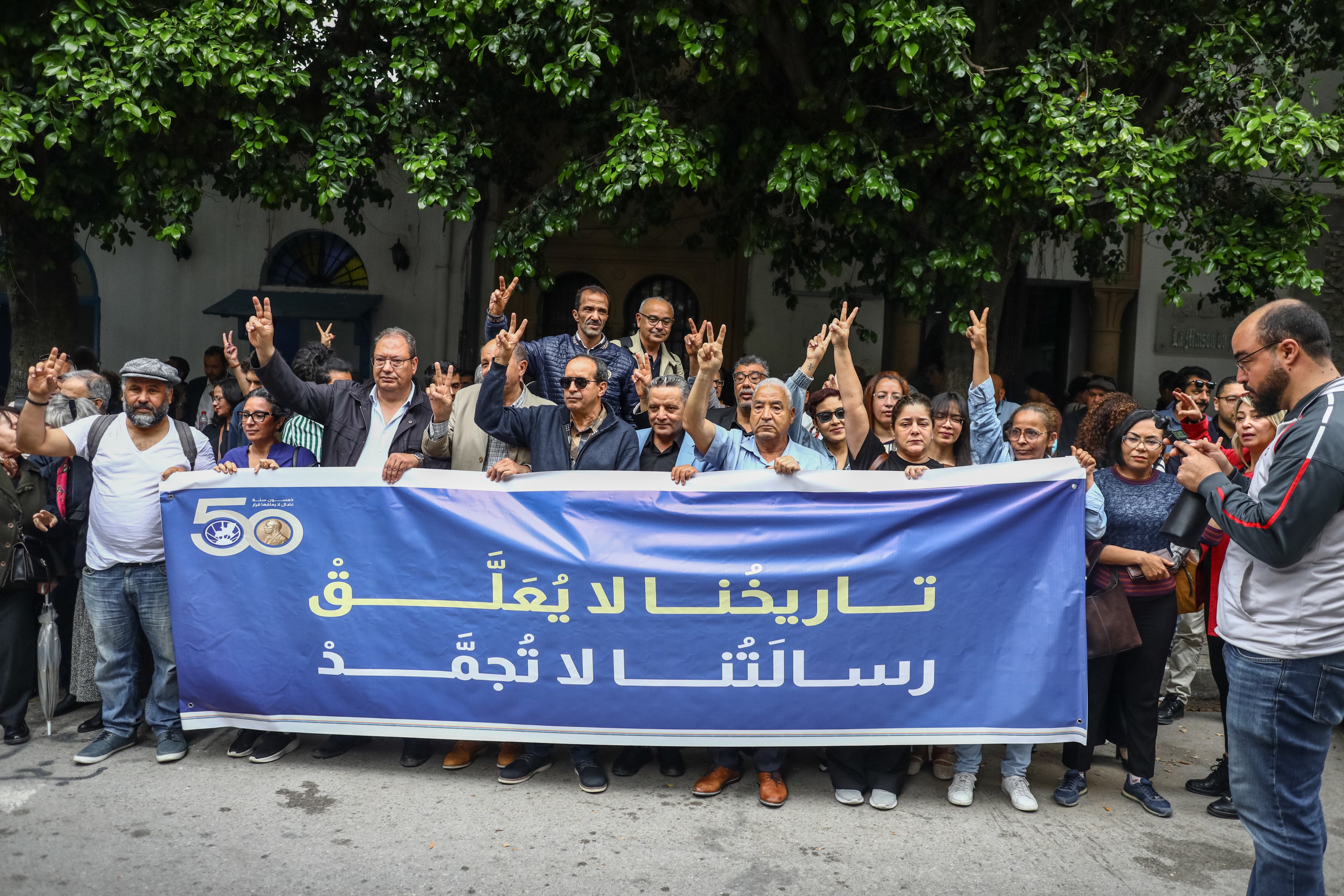 Demonstrators display a banner in Arabic reading, ''Our history will not be halted, and our message does not freeze,'' during a rally after Tunisian authorities suspended the Tunisian League for Human Rights, outside the court of First Instance in Tunis, May 6, 2026. 