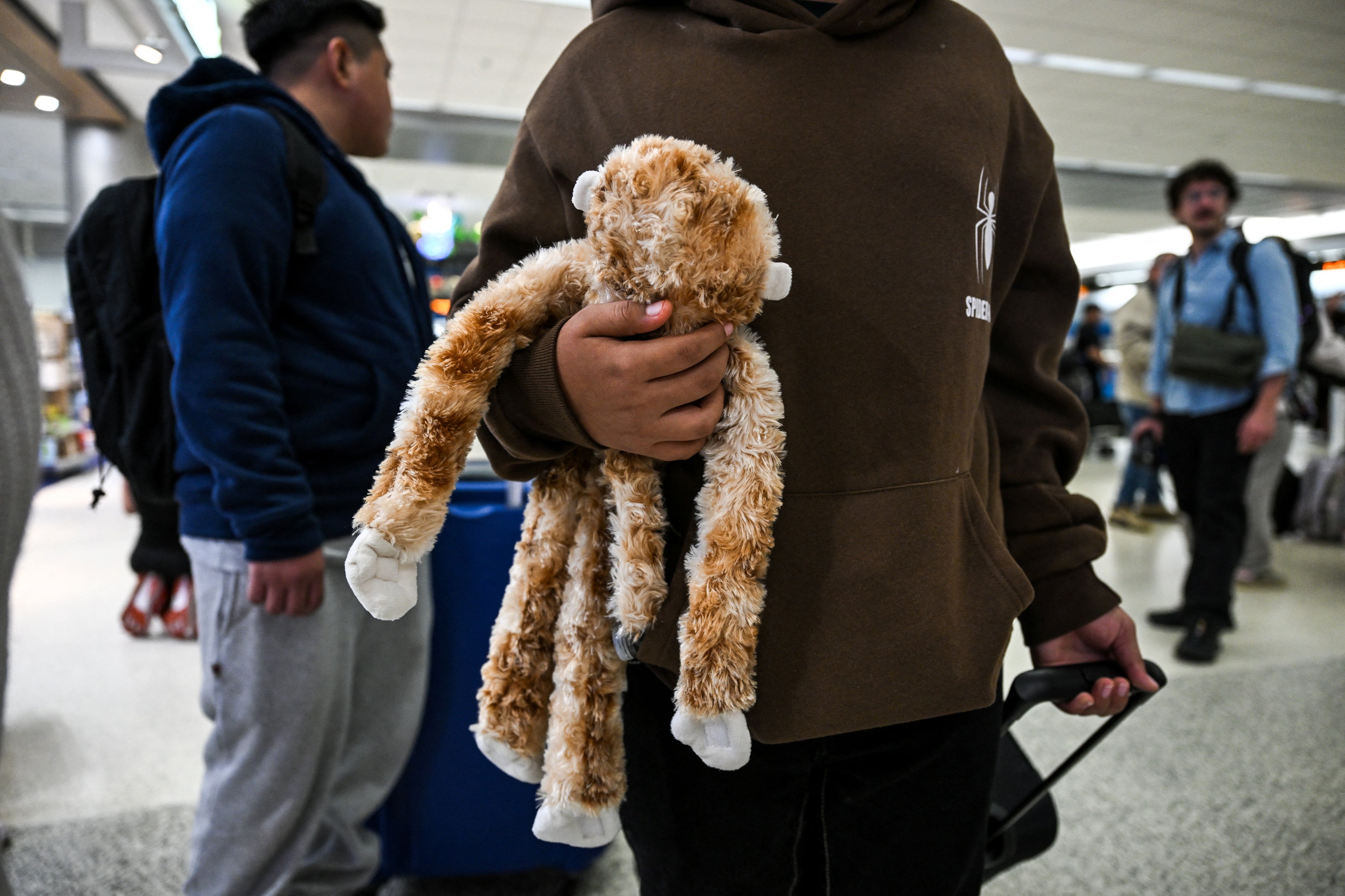 A child from Guatemala holds his stuffed monkey as he waits inside Miami International Airport to leave the United States and reunite with his recently deported parents in Guatemala, in Miami, Florida, December 4, 2025.